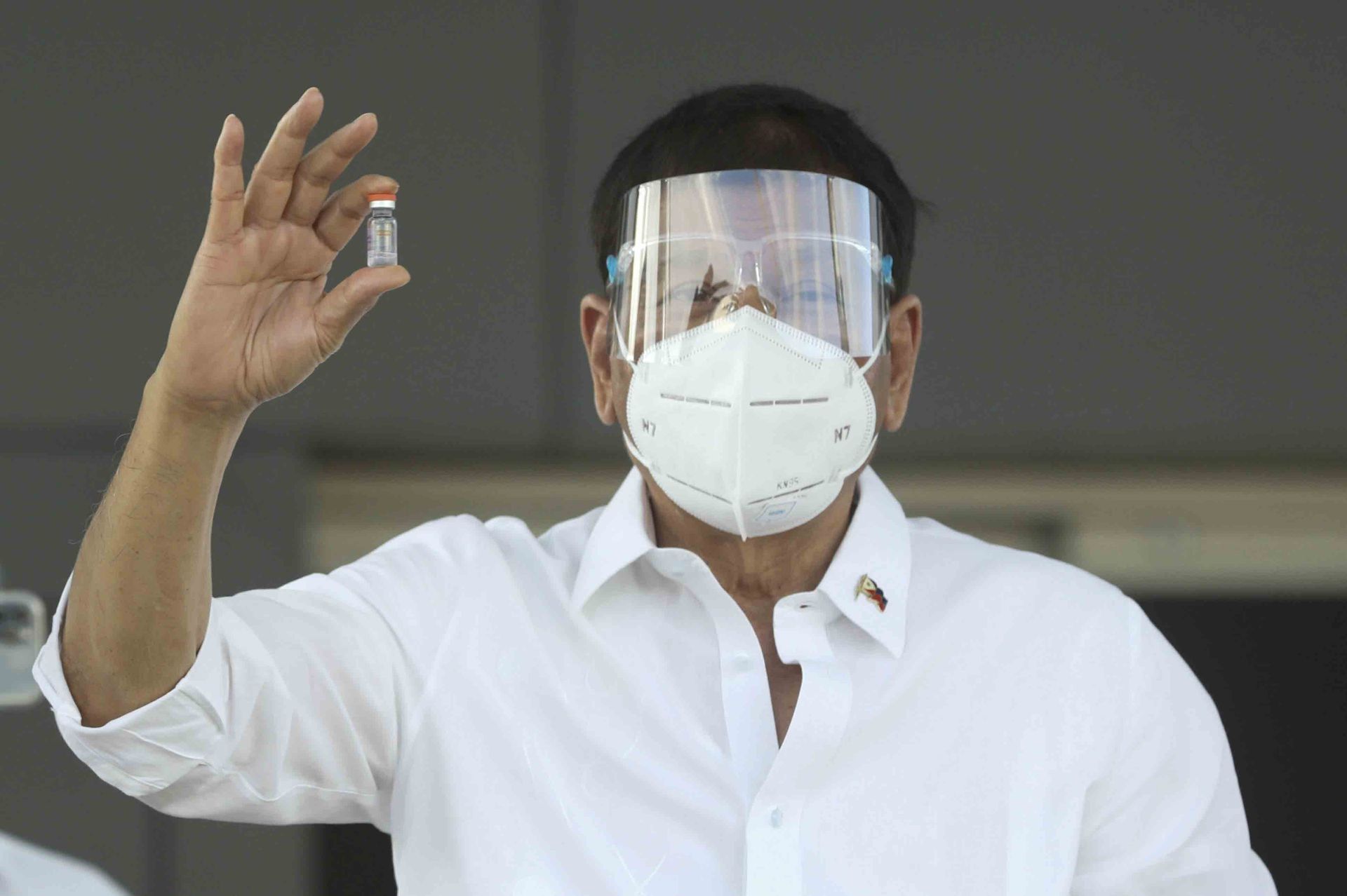 这张照片由马拉卡南总统摄影部提供，摄于2021年2月28日，当时菲律宾总统杜特尔特手拿一小瓶来自中国的科兴疫苗抵达菲律宾马尼拉维拉莫空军基地。（美联社）
