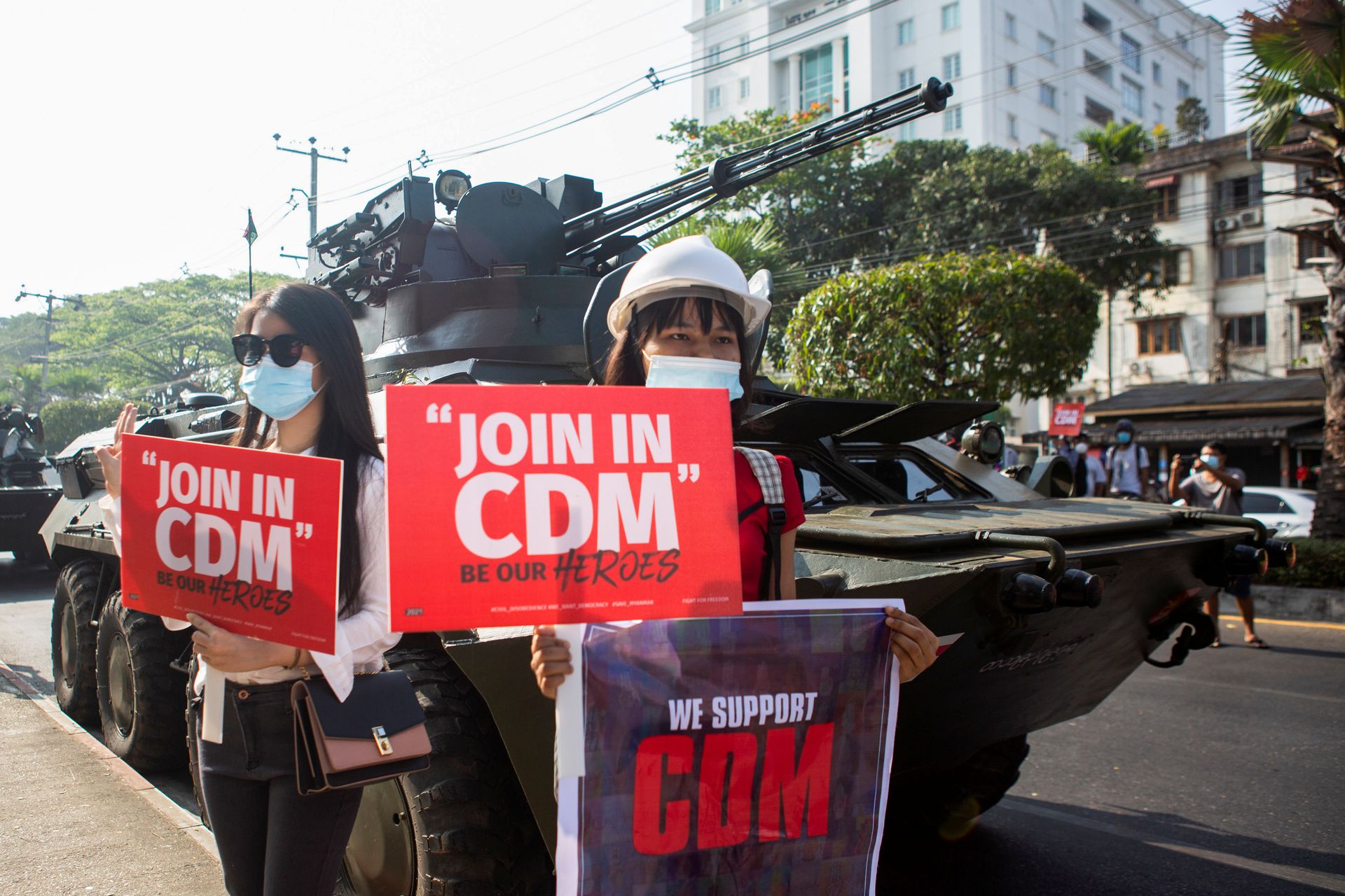 2月15日，在缅甸仰光，示威者在装甲车前举着写有“在CDM注册”标语牌，反对军事政变。（Reuters）
