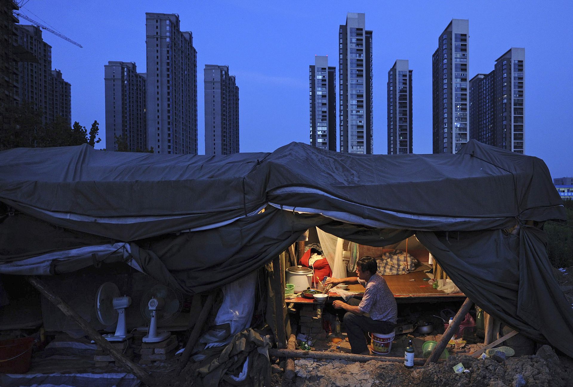 中国一位城市务工工人在工棚内吃饭。（Reuters）