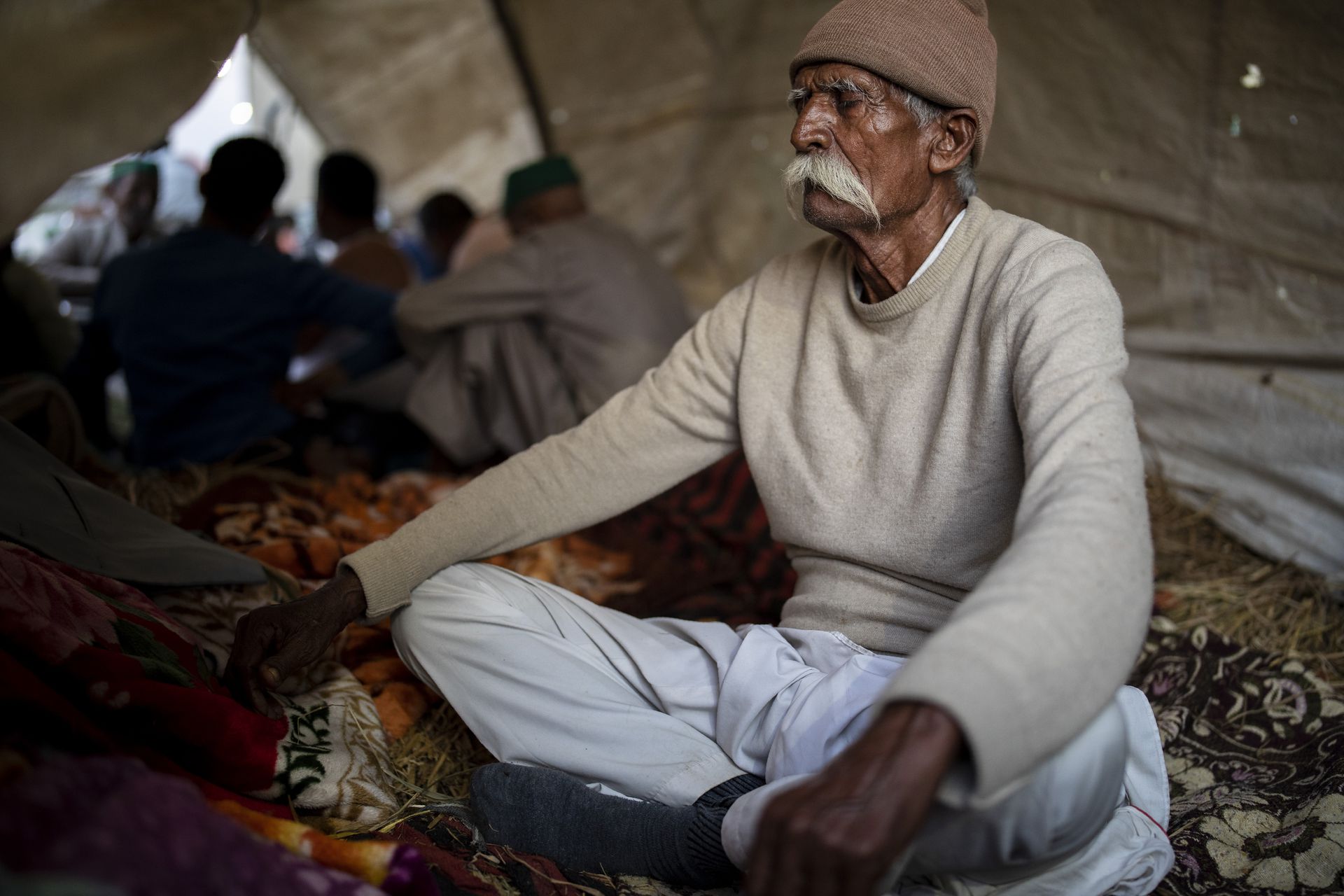 在印度德里和北方邦交界处，一名年长的农民坐在营地里沉思，抗议的农民封锁了一条主要公路。农民们担心，新的立法将减少他们的收入，并导致公司的剥削，最终使他们失去土地。（美联社）