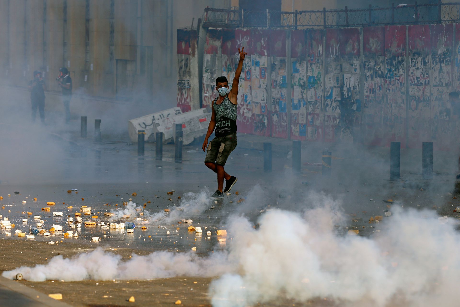 8月4日，在黎巴嫩贝鲁特议会广场附近的贝鲁特港口大规模爆炸一周年的抗议活动中，一名反政府抗议者在防暴警察发射催泪瓦斯的情况下举起挑衅手势。（AP）