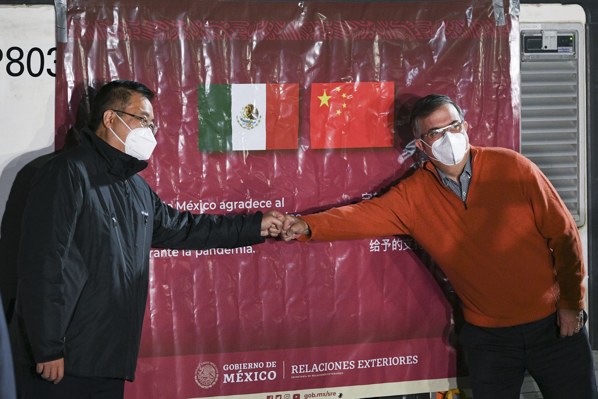 2月27日，在墨西哥首都墨西哥城国际机场，墨西哥外交部长埃布拉德（右）和中国驻墨西哥大使祝青桥在装有中国科兴新冠疫苗的温控集装箱前合影。（新华社）