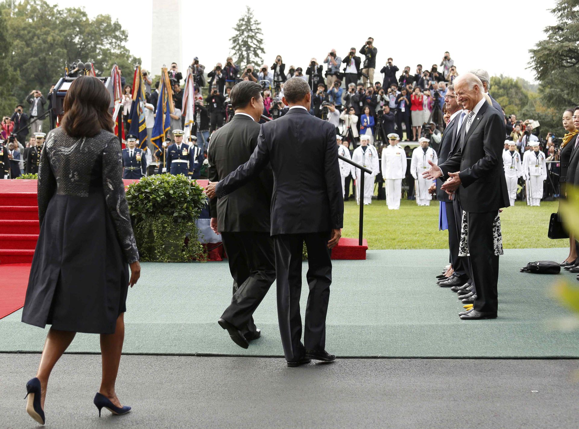2015年9月25日，时任总统奥巴马在白宫南草坪举行隆重仪式，欢迎习近平对美国进行国事访问。图中奥巴马环臂护住习近平一同前行，笑容灿烂的拜登等在那里，双手摊开，翘首以盼，奥巴马和拜登展开的魅力攻势可见一斑。（Reuters）