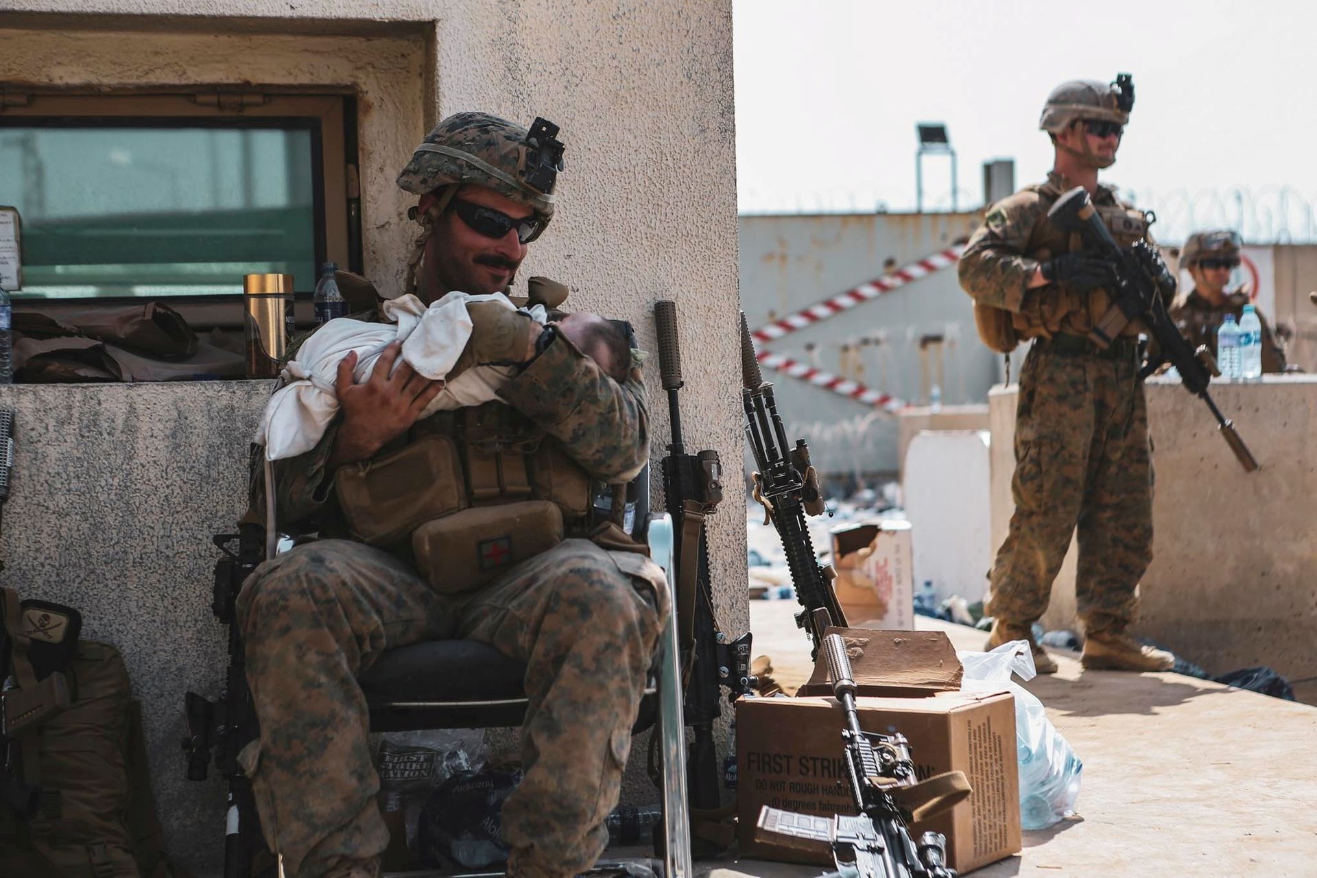2021 年 8 月 20 日拍摄的这张照片中，一名被分配到第 24 海军陆战队远征部队 (MEU) 的美国海军陆战队员在阿富汗喀布尔的哈米德卡尔扎伊国际机场撤离期间抱着一个婴儿。（Reuters）