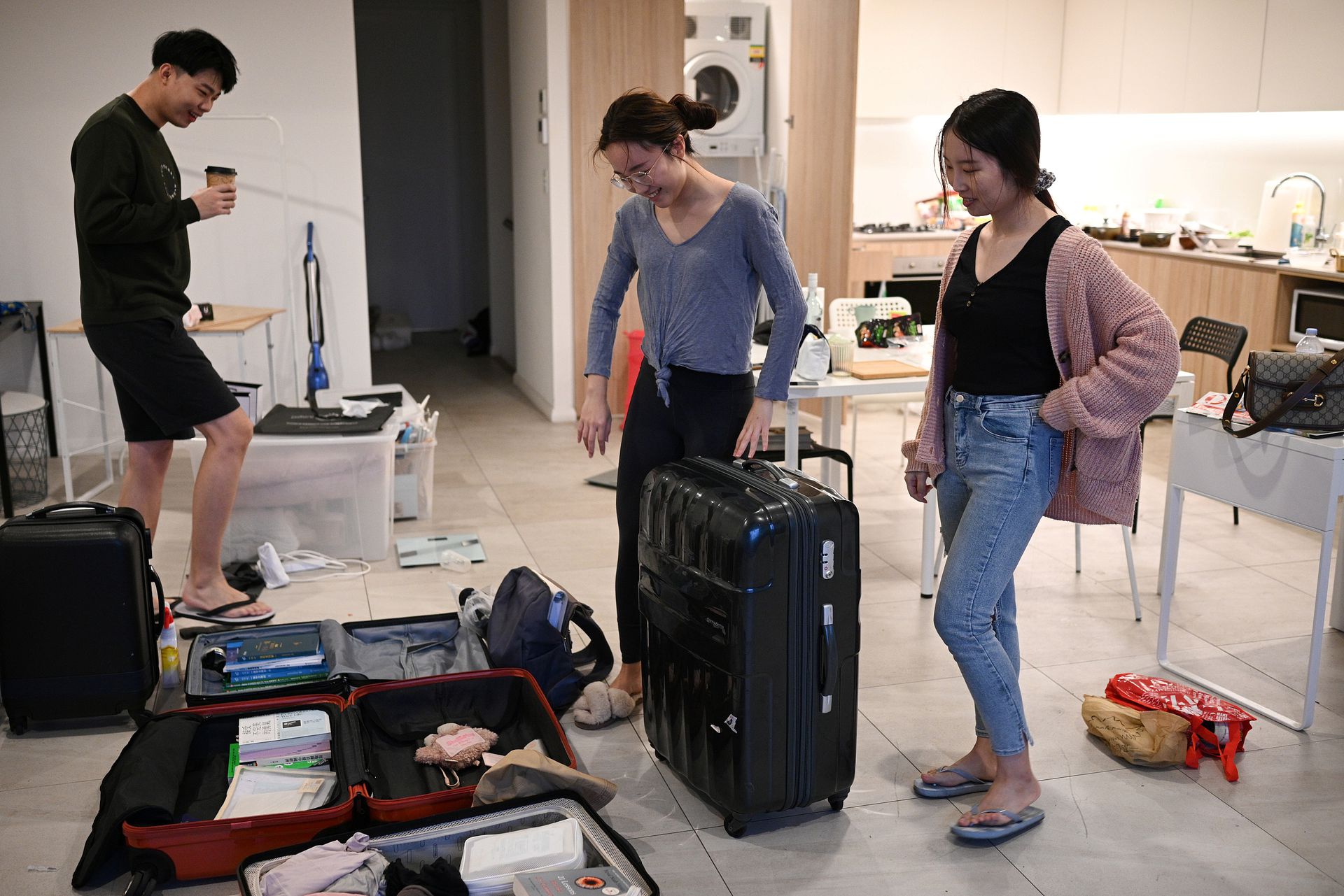 中国留学生Sunny Gu（左）和女友Maggie Zhang（右）与室友Siyan Zhu交流。Siyan Zhu也来自中国，正在打包行李准备返回中国。（人民视觉）