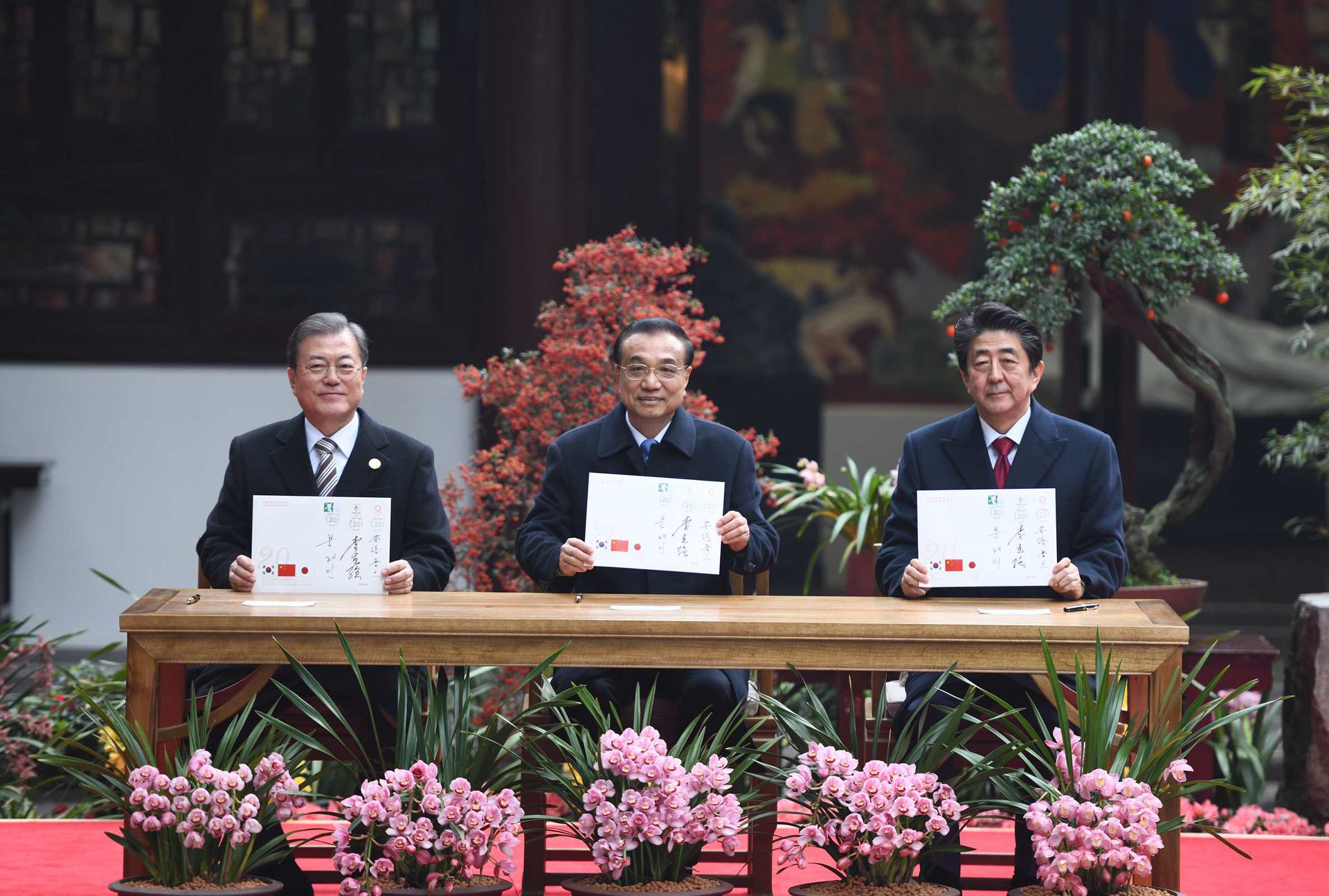 2019年12月24日，李克强（中）与文在寅（左）、安倍晋三出席“中日韩合作20周年纪念封”发行仪式。（新华社）