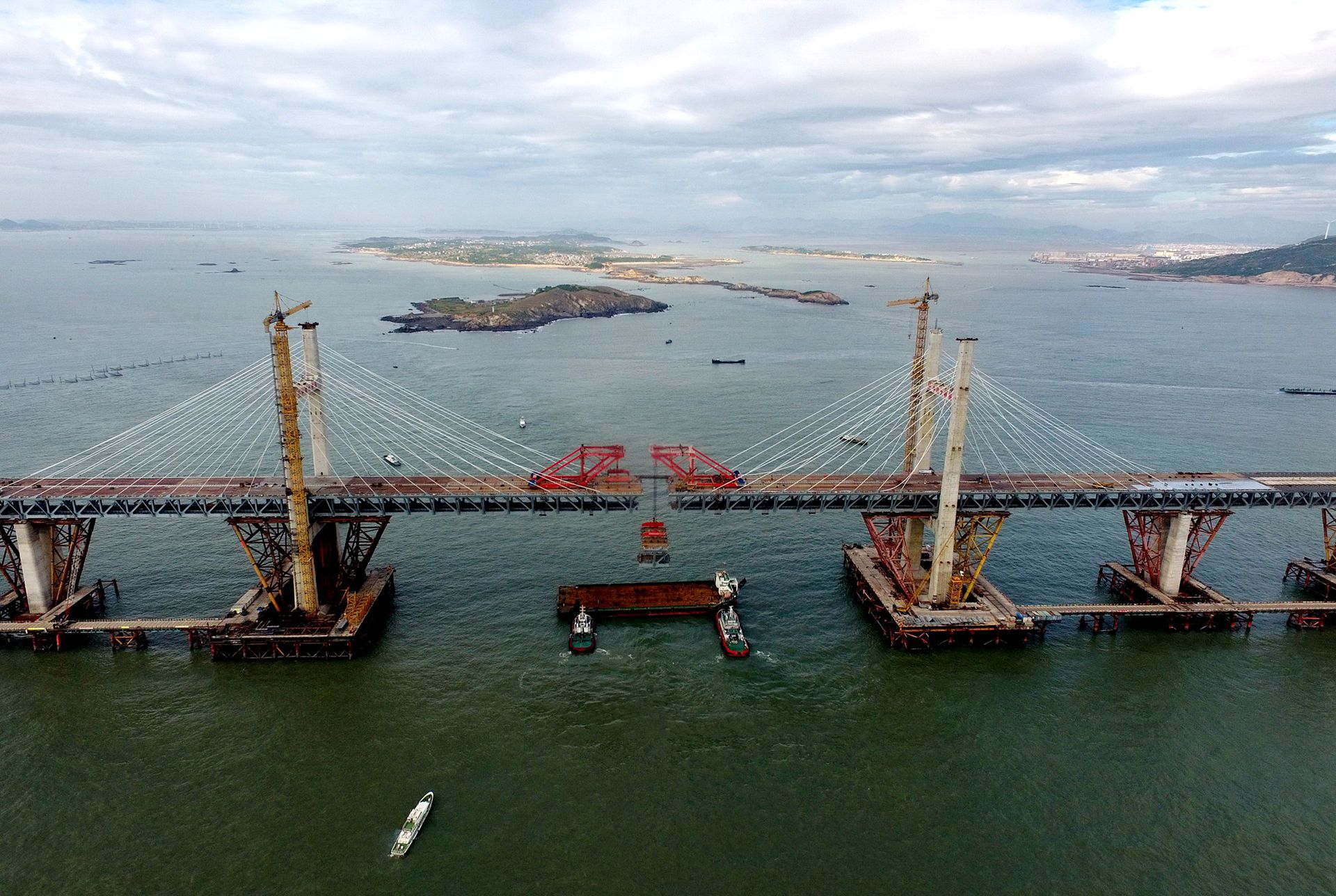 2019年9月21日，平潭海峡公铁大桥鼓屿门航道桥钢桁梁被架梁起重机稳稳地提升起来。（新华社）