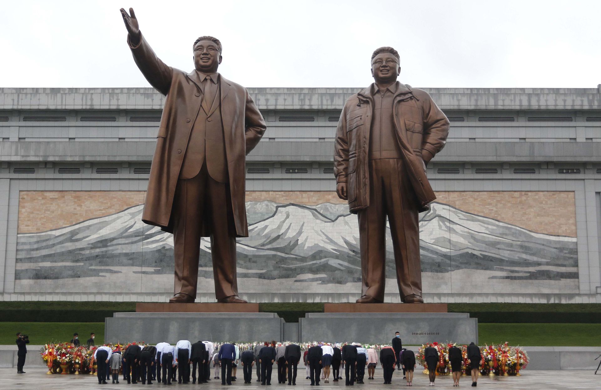 图为2021年10月10日，在朝鲜平壤劳动党成立76周年之际，朝鲜儿童联盟成员参观了位于万寿山的朝鲜领导人金日成和金正日的雕像。（AP）