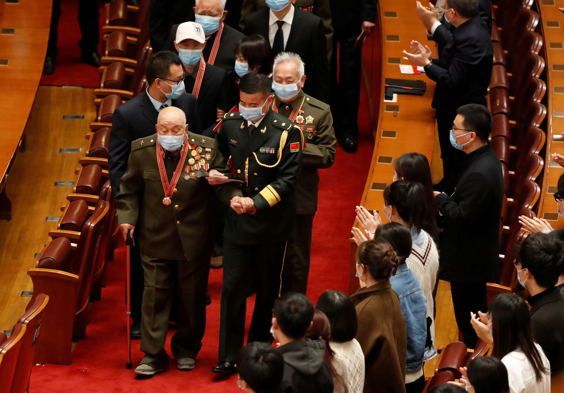 与会者欢迎志愿军老兵步入会场。(路透社) 与会者欢迎志愿军老兵步入会场。(路透社)