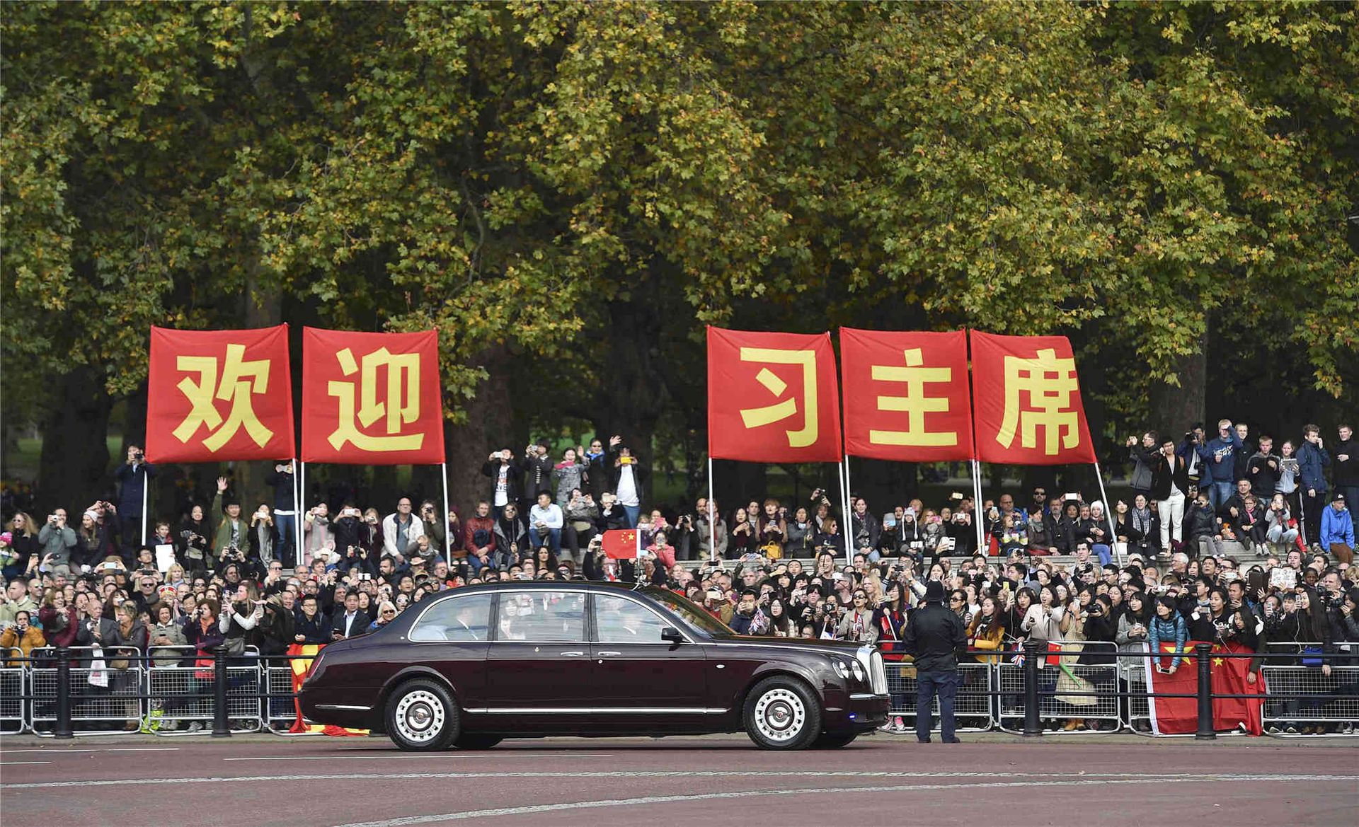 2015年10月20日，中國國家主席習近平訪問英國，一些民眾舉著歡迎習近平的標語站在路旁。（Reuters）