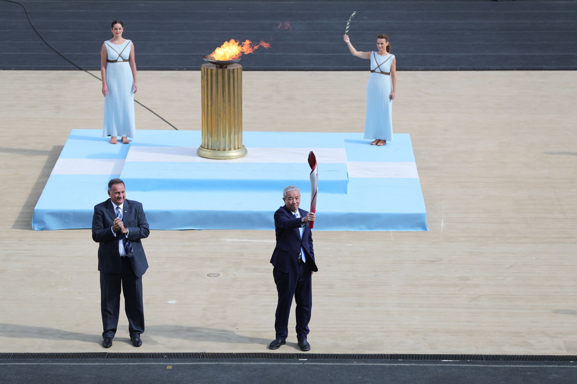 2021年10月19日，北京冬奥组委特别代表、北京冬奥组委副主席于再清（前右）展示2022年北京冬季奥运会火炬。（新华社）