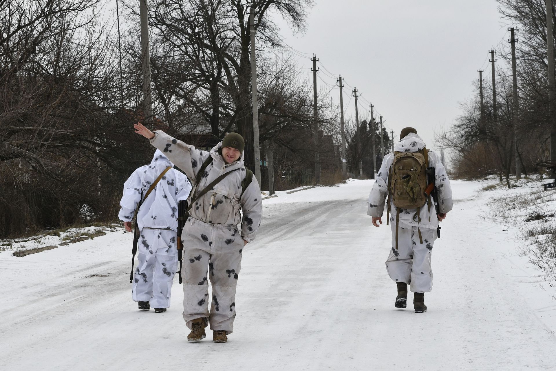 2022年1月22日，在乌克兰东部顿涅茨克地区Yasynuvata区的Verkhnotoretske村，一名乌克兰军人和他的战友在一条街道上与俄罗斯支持的分离主义分子一起向前线巡逻时挥手致意。（A)