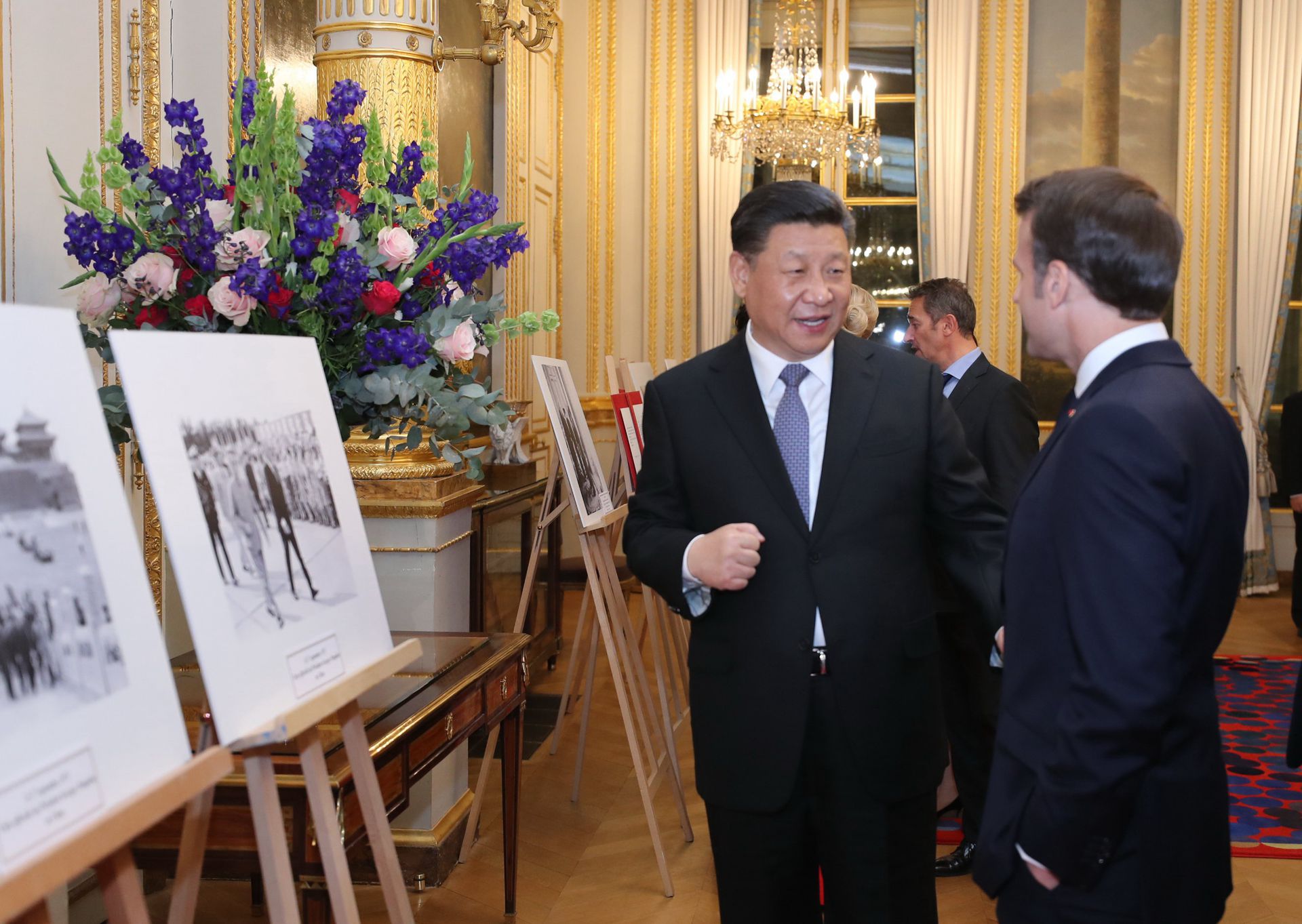 2019年3月25日，中国国家主席习近平在巴黎爱丽舍宫同法国总统马克龙参观中法建交55周年和留法勤工俭学运动100周年图片展。 （新华社）