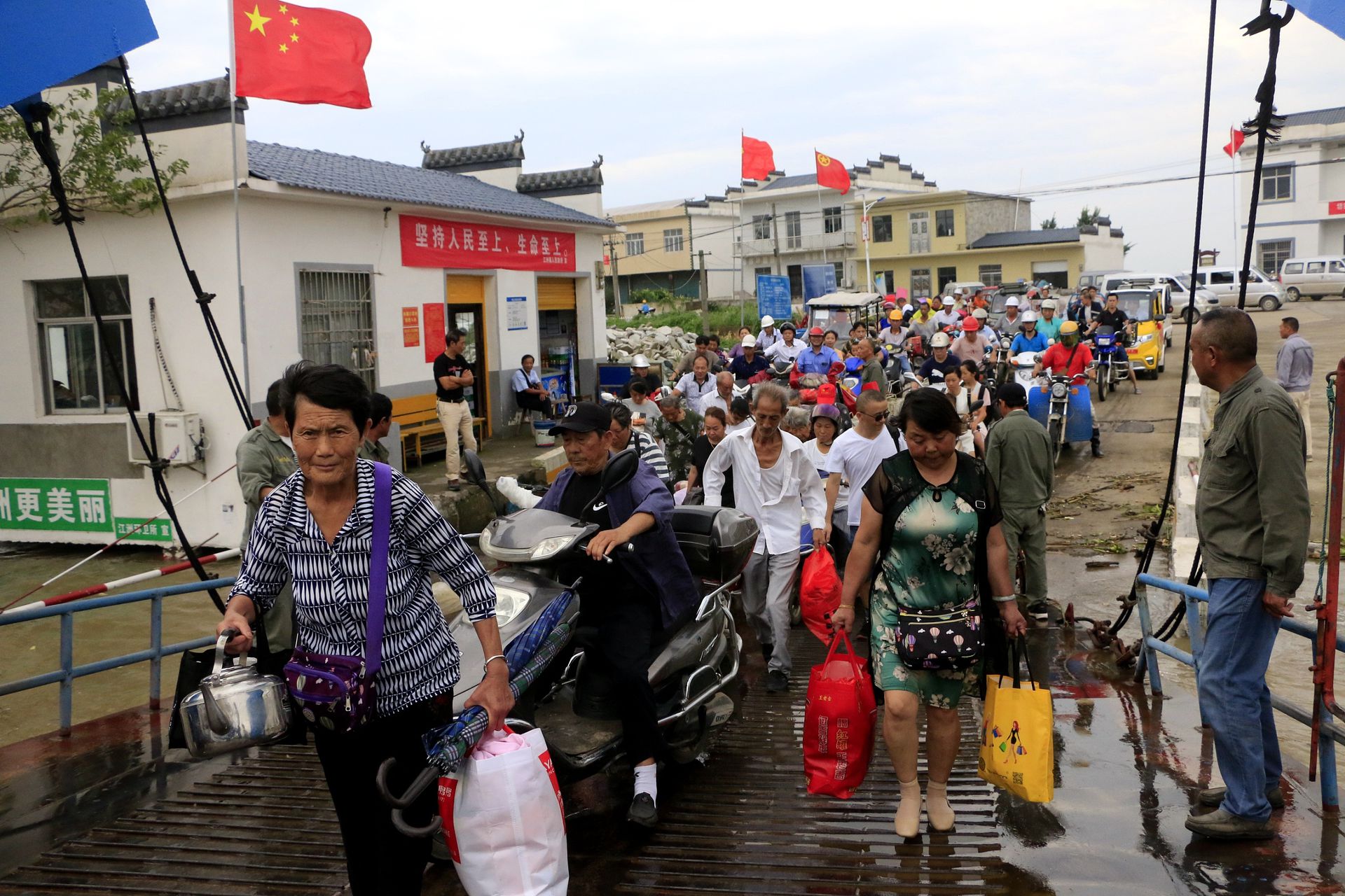 为应对此次洪灾，中国政府已经启动应急预案，大量民众被疏散正在被疏散。图为7月11日，位于江西省九江市地势低洼地段的民众正在进行有序转移。（人民视觉）