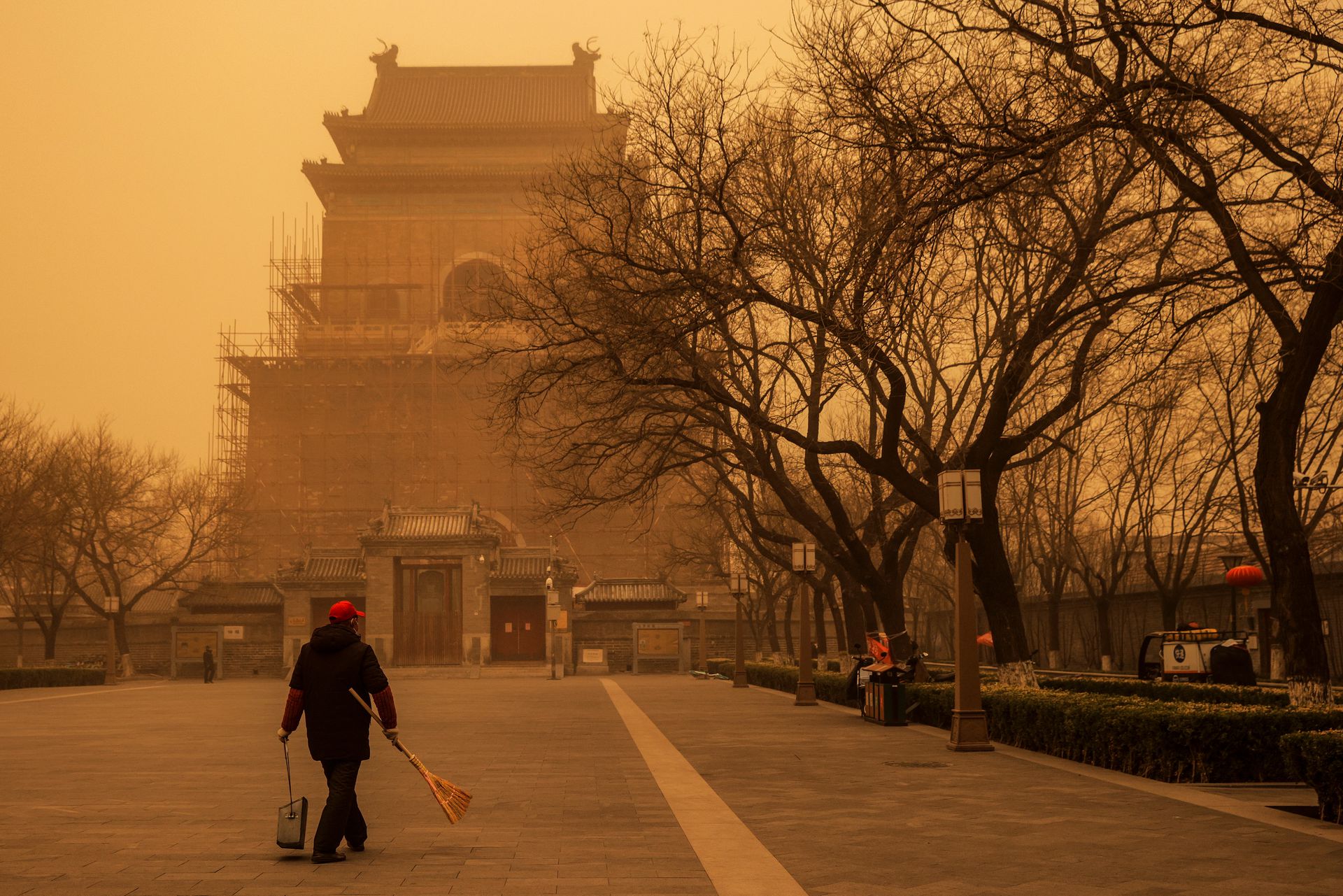 2021年3月15日，当中国北京遭遇沙尘暴时，一个人拿着扫帚和簸箕在早高峰时间行走。（Reuters）