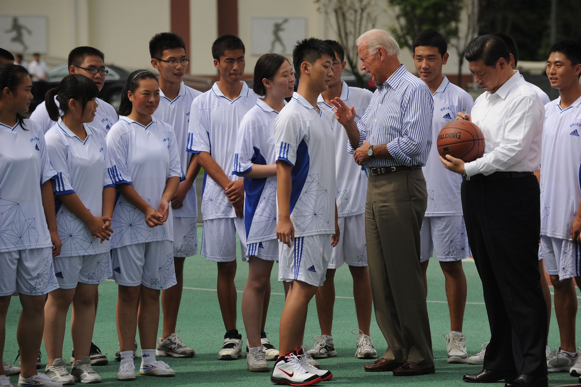 2011年8月21日，习近平与拜登一起参观四川汶川地震后重建的都江堰青城山高级中学，与学生交流互动，在NBA赠送篮球上签名。（Getty）