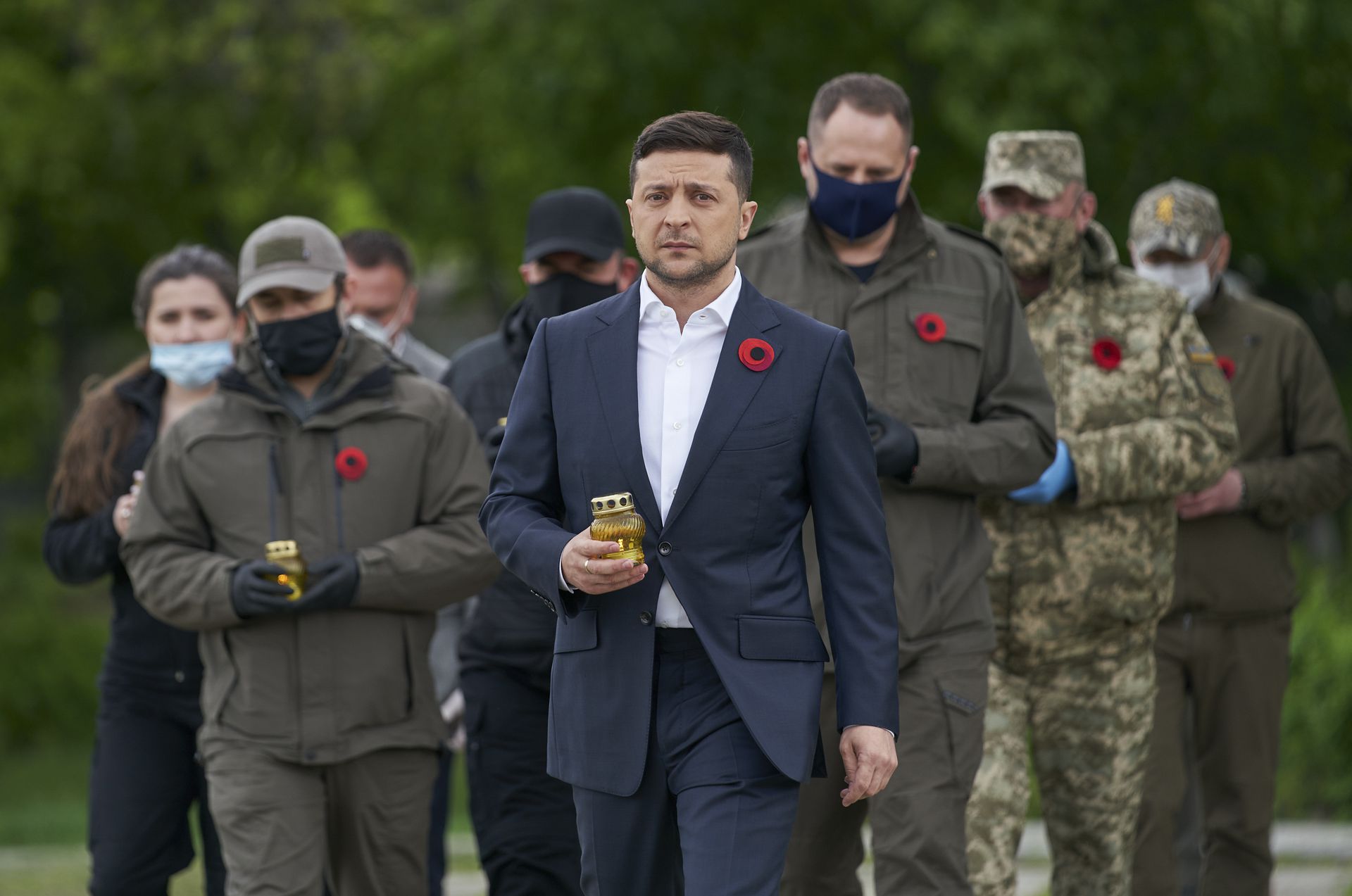 乌克兰总统泽连斯基（中）和戴着口罩的官员们手持蜡烛，前往卢甘斯克地区凭吊，这位演员出身的元首相当上镜，但遗憾的是，乌克兰政治不是新一季的《人民公仆》，演砸了不能重来。（美联社）