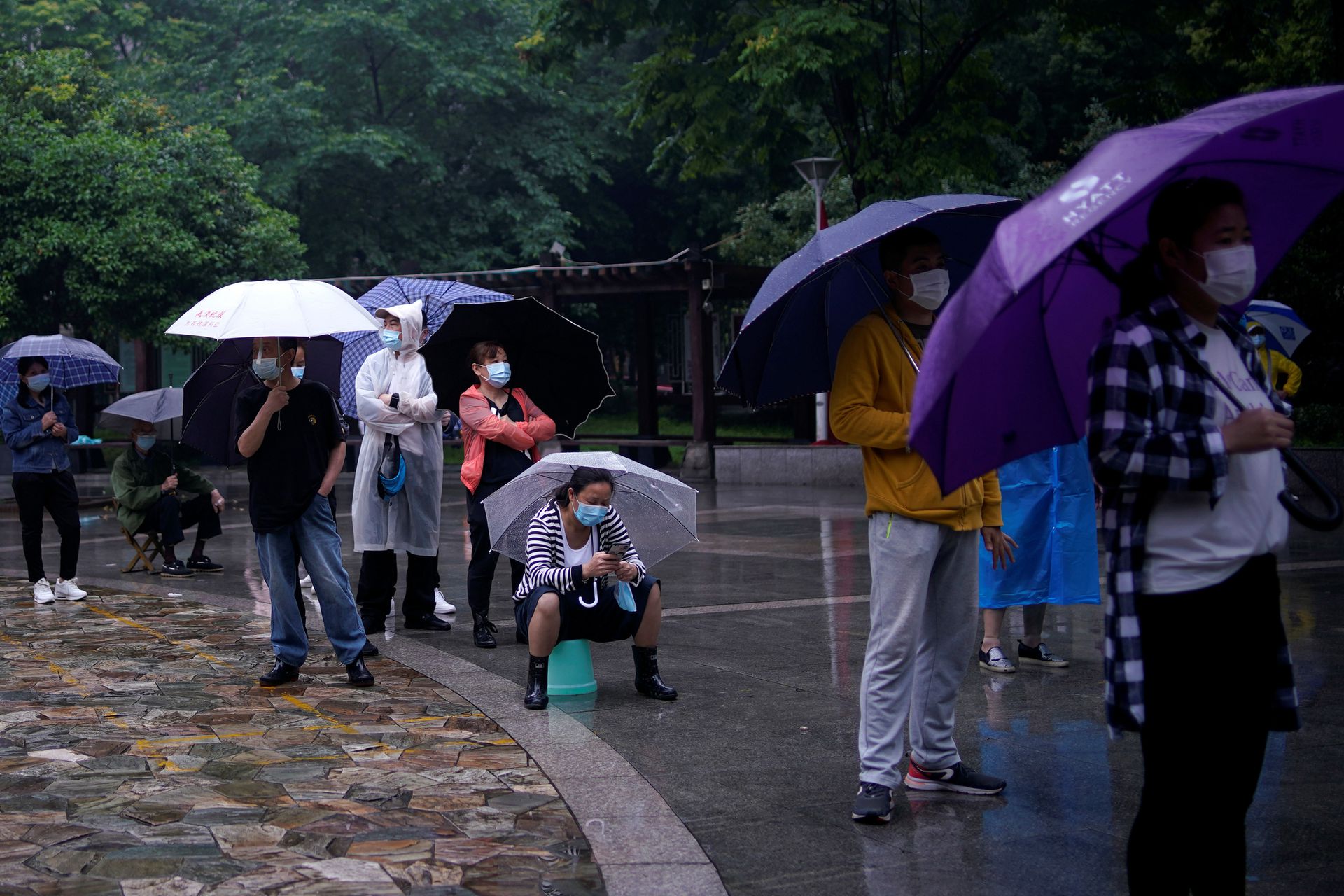 5月14日武汉,居民们戴着口罩在雨中排队进行核酸检测。(Reuters)