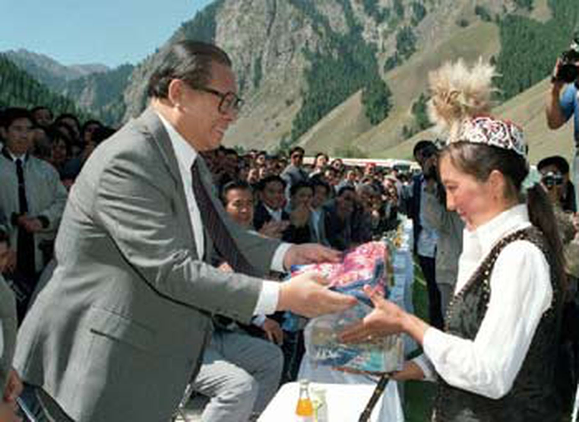 1990年，江泽民在乌鲁木齐市郊南山观看哈萨克牧民进行的赛马、姑娘追、刁羊比赛后，向赢得赛马比赛第一名的哈萨克姑娘发奖。（新华社）