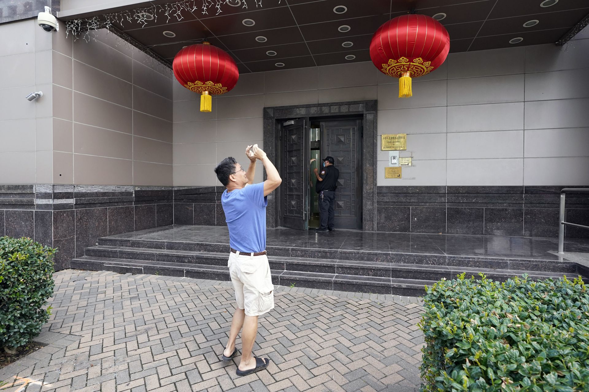 一名中国驻休斯敦总领馆人员拍照，远处疑似是一名美国警方人员。（AP）