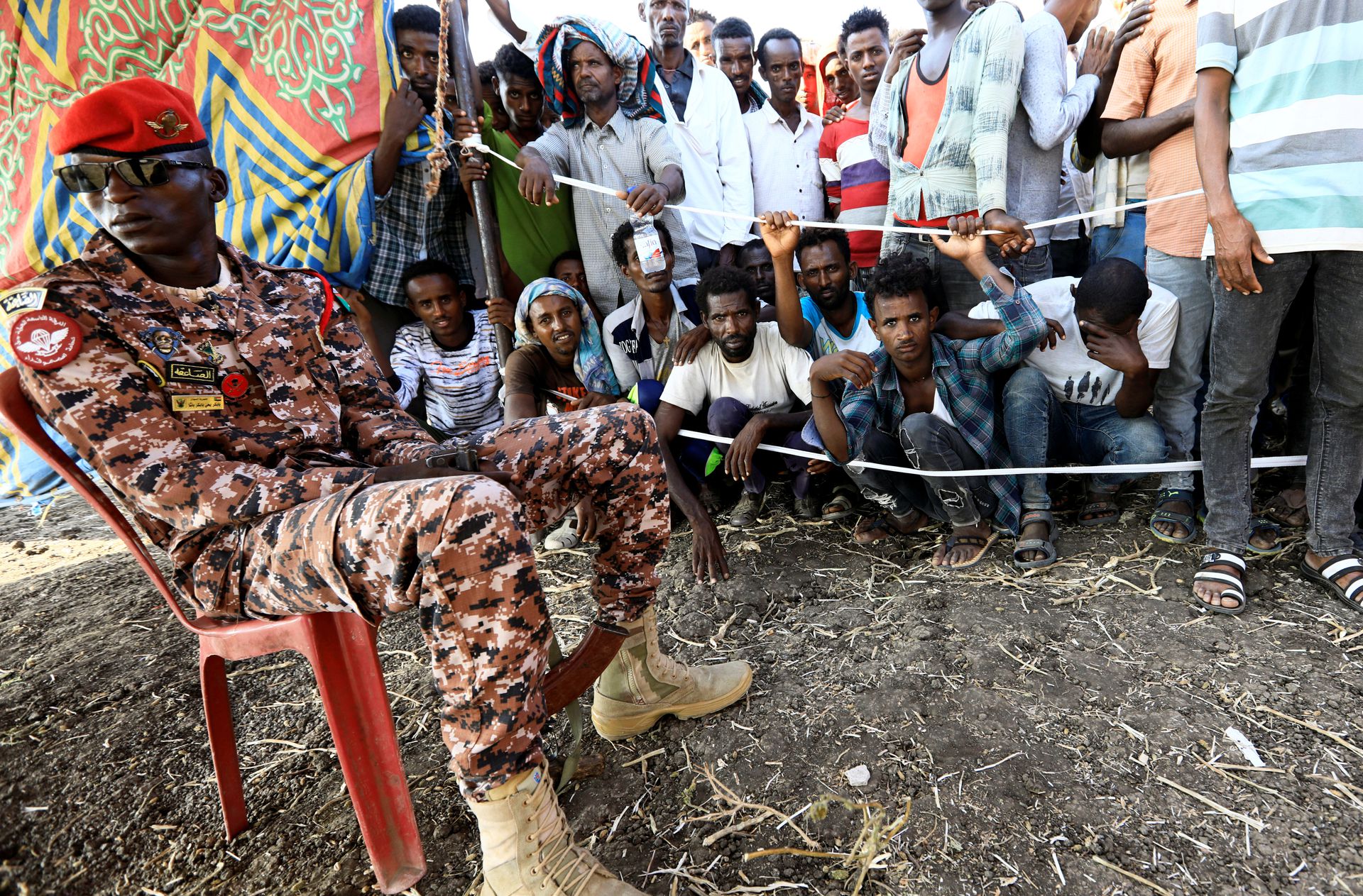 2020年11月20日，苏丹Al-Qadarif州，在苏丹与埃塞俄比亚边境的Fashaga难民营，一名苏丹军官在守卫逃离提格雷地区战争的埃塞俄比亚人，他们聚集在那里接受来自世界粮食计划署的救援物资。（Reuters)
