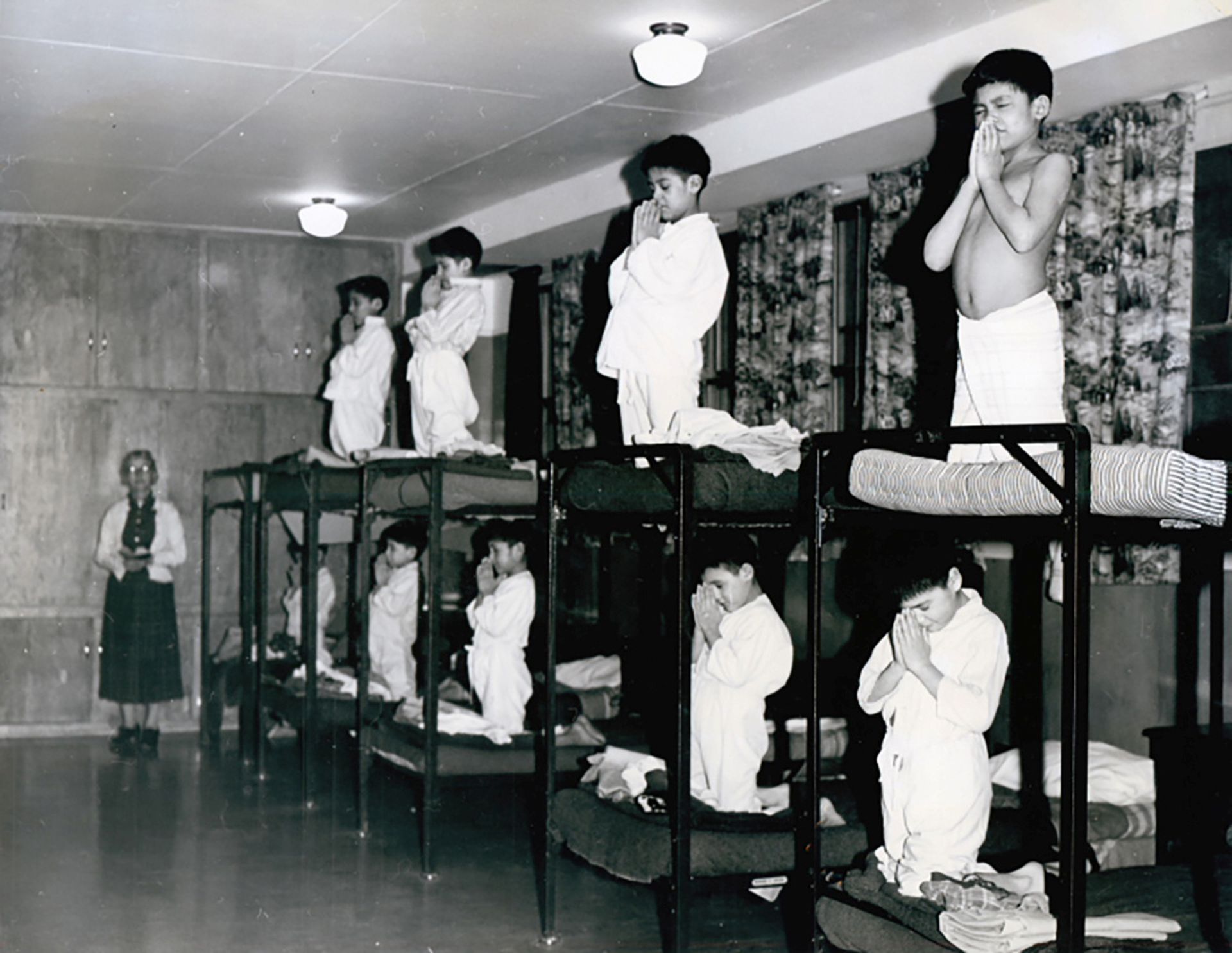 1950年，加拿大安大略省寄宿学校Bishop Horden Memorial School的宿舍里，男孩们在双层床上祈祷。（Reuters）