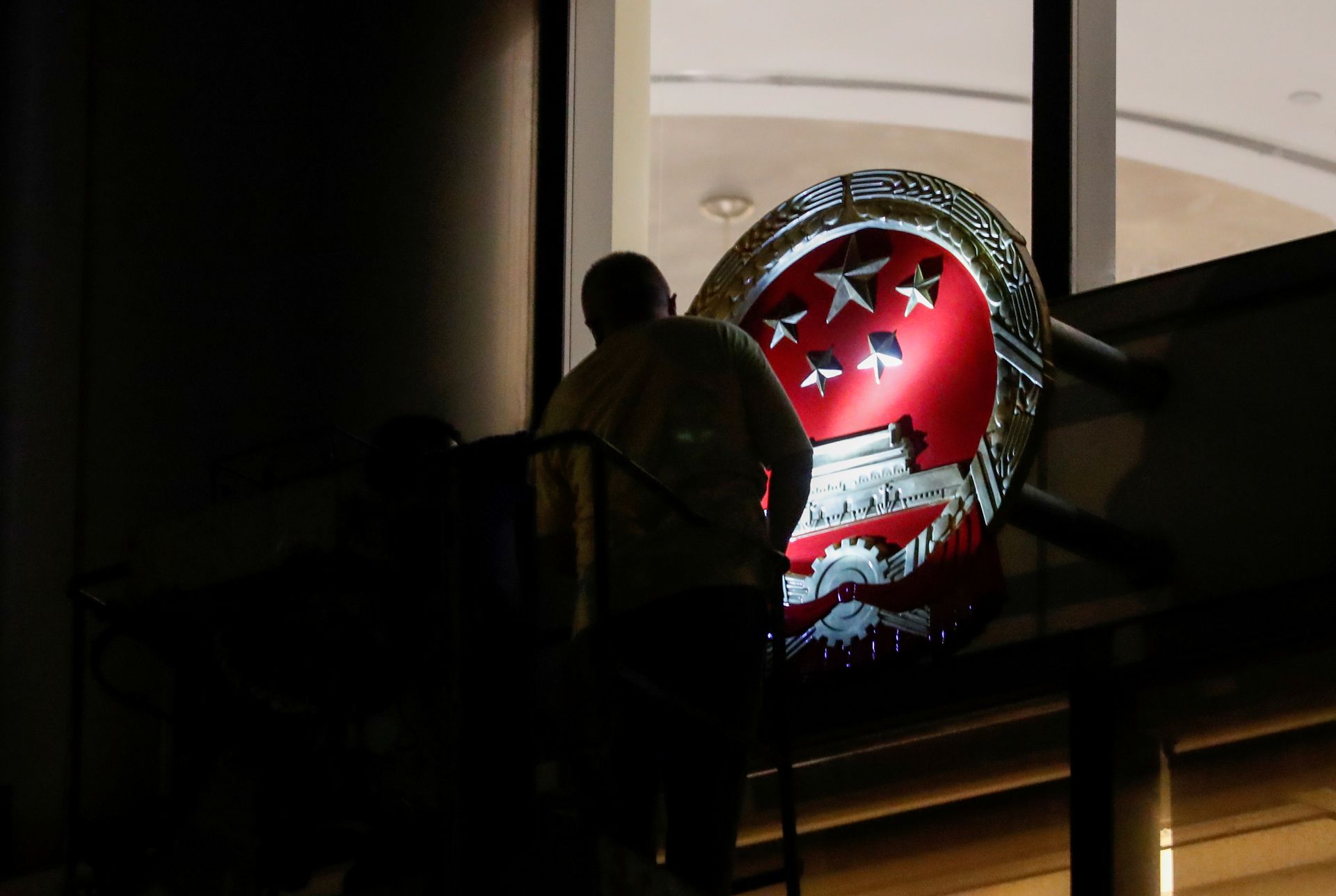 7月8日，中国中央人民政府驻香港特别行政区维护国家安全公署在香港揭牌。图为当地时间7月8日午夜，工作人员在香港铜锣湾维景酒店外放置国徽。（Reuters）