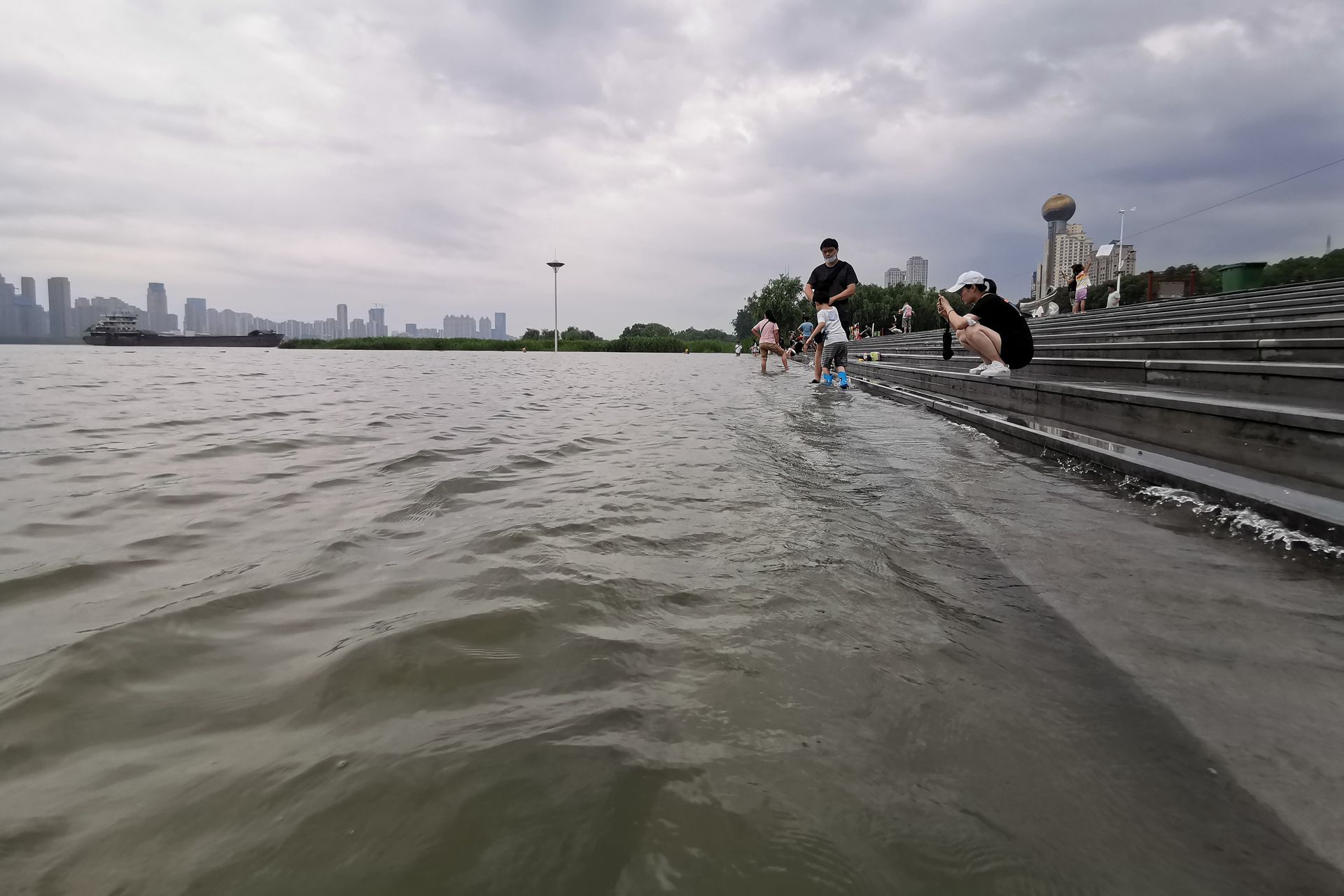 长江干堤的稳固保证了长江大中城市的安全。图为6月28日，长江武汉段水位上涨已经漫上汉口江滩亲水平台。但是，市民并没有感到危险和紧张，反而是在江边观景、拍照、戏水、游泳。（视觉中国 ）