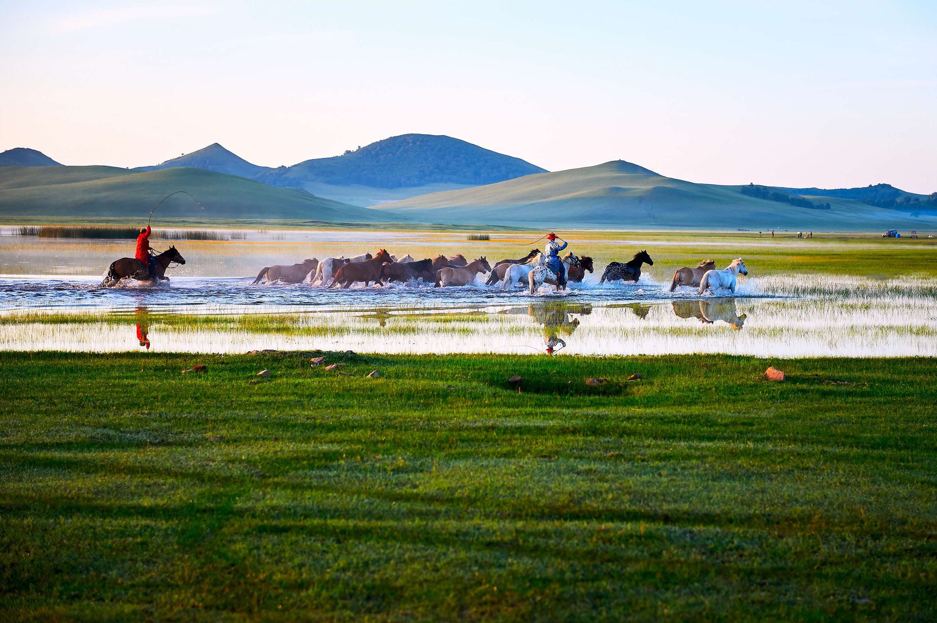内蒙古以广袤的草原著称。图为2016年8月3日内蒙古自治区赤峰市克什克腾旗乌兰布统乡坝上草原日出时分，牧人驱赶马群通过将军泡子。（VCG）