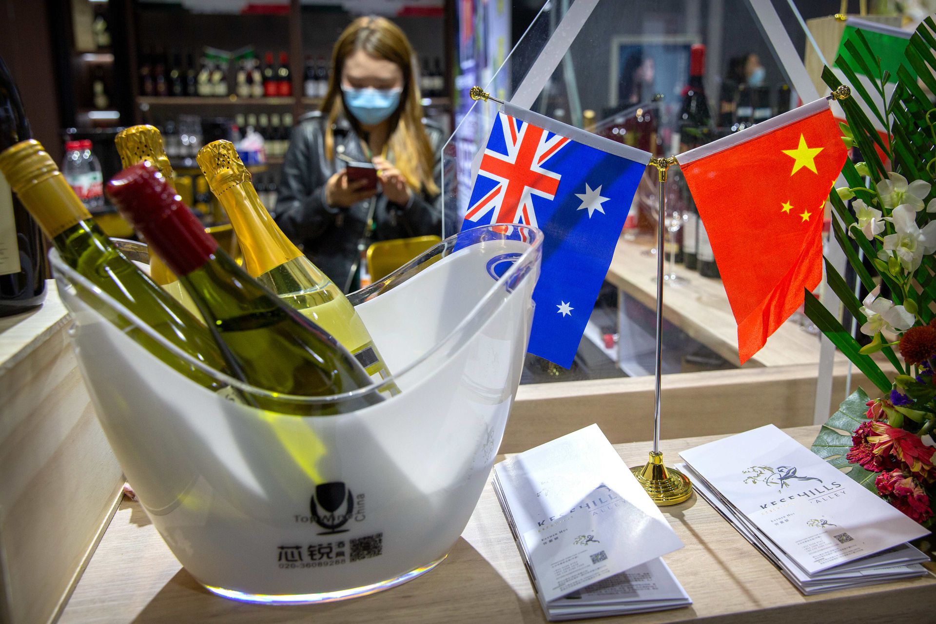 2020年11月5日，在上海举行的中国国际进口博览会上，一名戴着口罩的工作人员站在展示澳大利亚葡萄酒的展台旁。（AP）