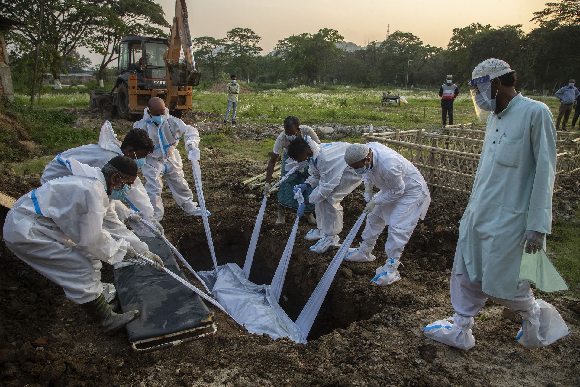 在印度高哈蒂，身着防护服的亲戚和工作人员正在埋葬一名新冠肺炎死者。（AP）