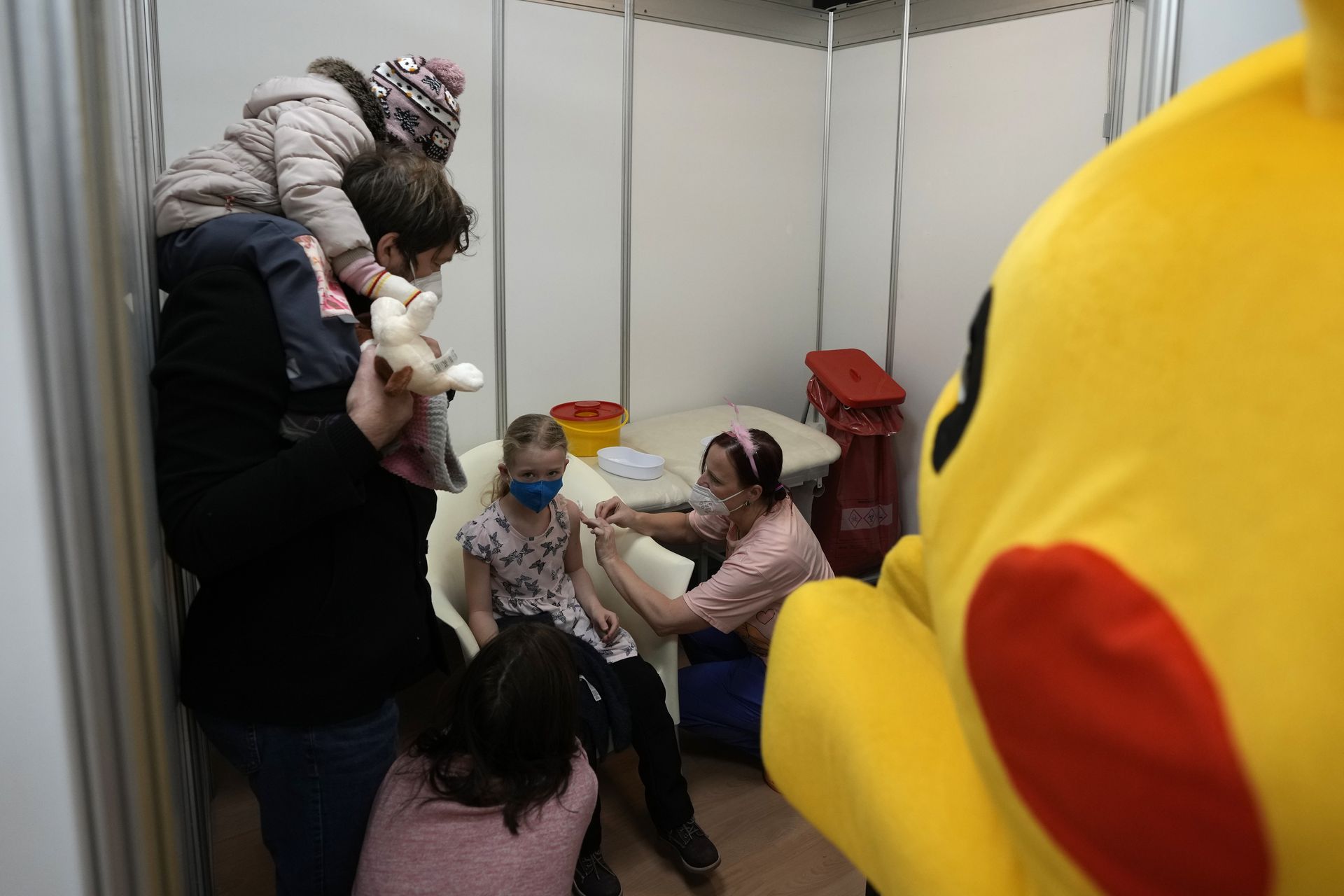 图为1月8日，捷克布拉格一间疫苗接种中心。工作人员身穿布娃娃服饰，逗小孩接种疫苗。（AP）