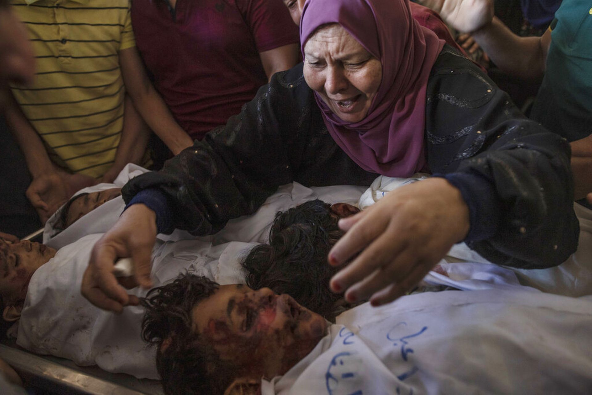 以色列空袭加沙北部拜特拉希耶后，巴勒斯坦有4兄弟死亡，他们的遗体被埋在房屋瓦砾中，图为5月14日死者亲属看着遗体，悲痛欲绝。（AP）