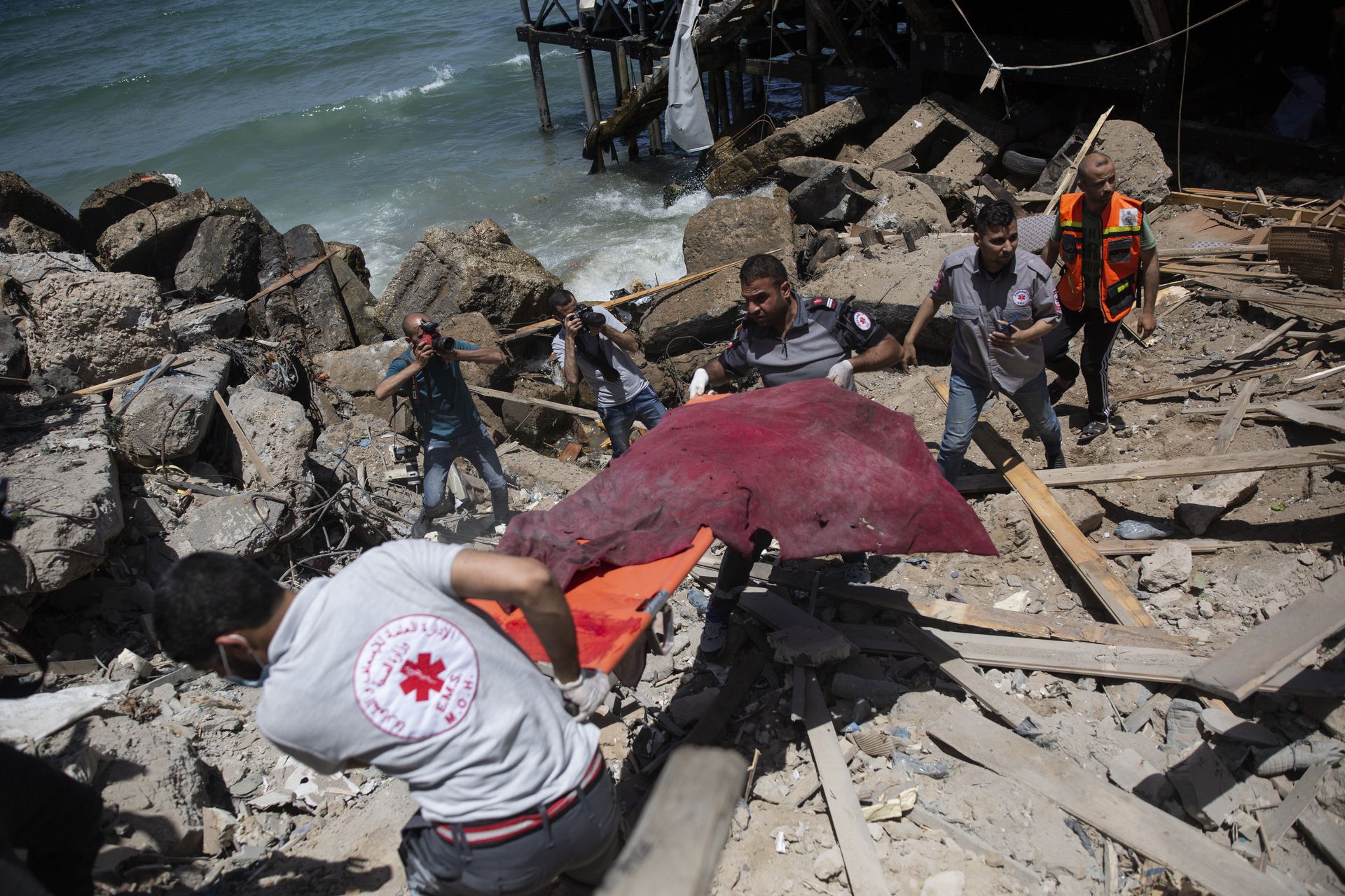 5月17日，巴勒斯坦救援人员在加沙城一个位处海边的咖啡店旁，找到一名死于空袭的男子。（AP）