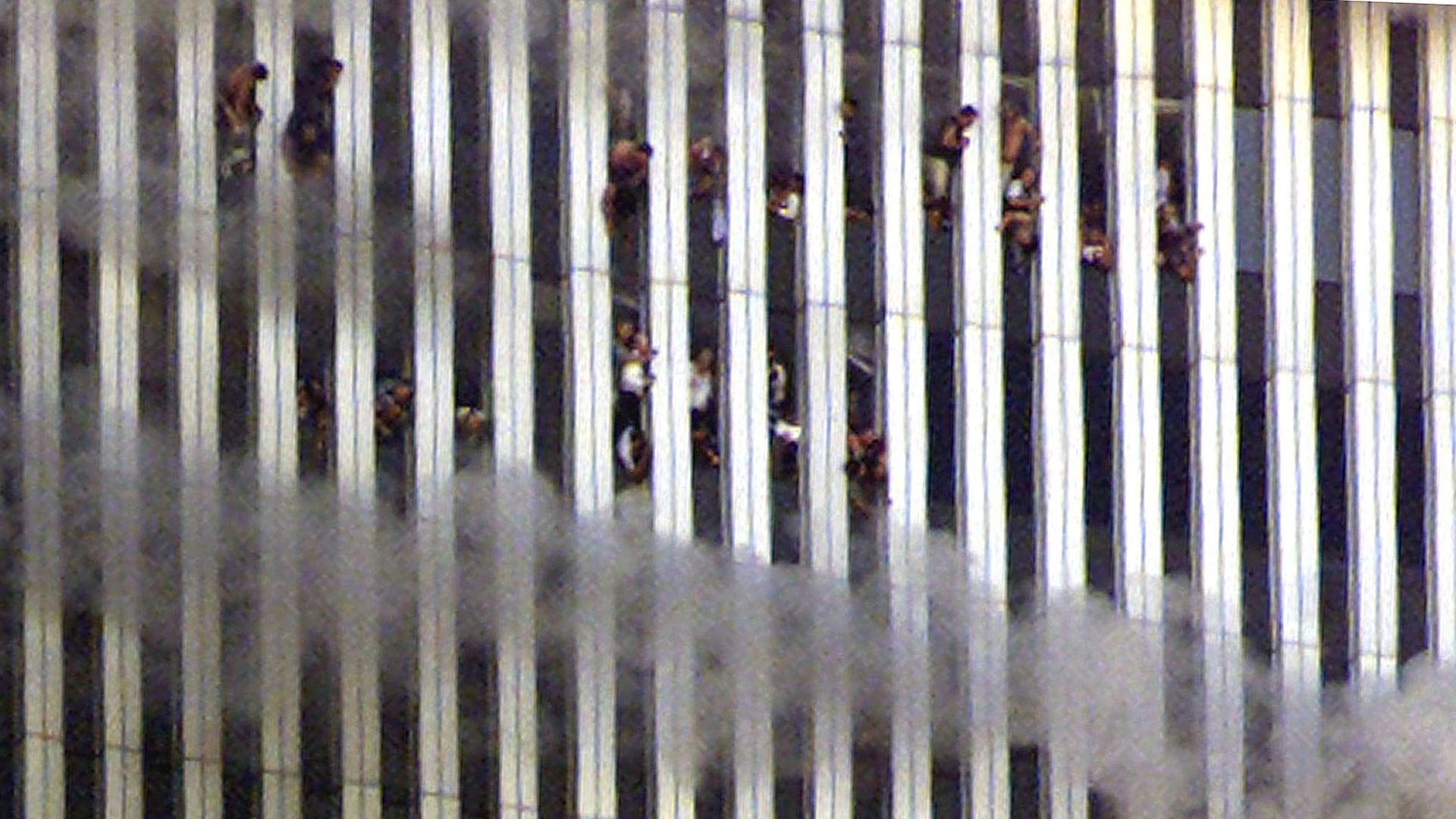 “9·11”二十周年：美国纽约世界贸易中心双子塔2001年9月11日遇袭，大楼其后起火，浓烟迅速漫延。当时两幢大楼有大量上班族被困，很多人因受不了高温煎熬而堕楼或跳楼。政府估计，当时约有50至逾200人在世贸中心堕楼身亡。图为当天镜头下，身在北座大楼内的人站在窗前。（Reuters）