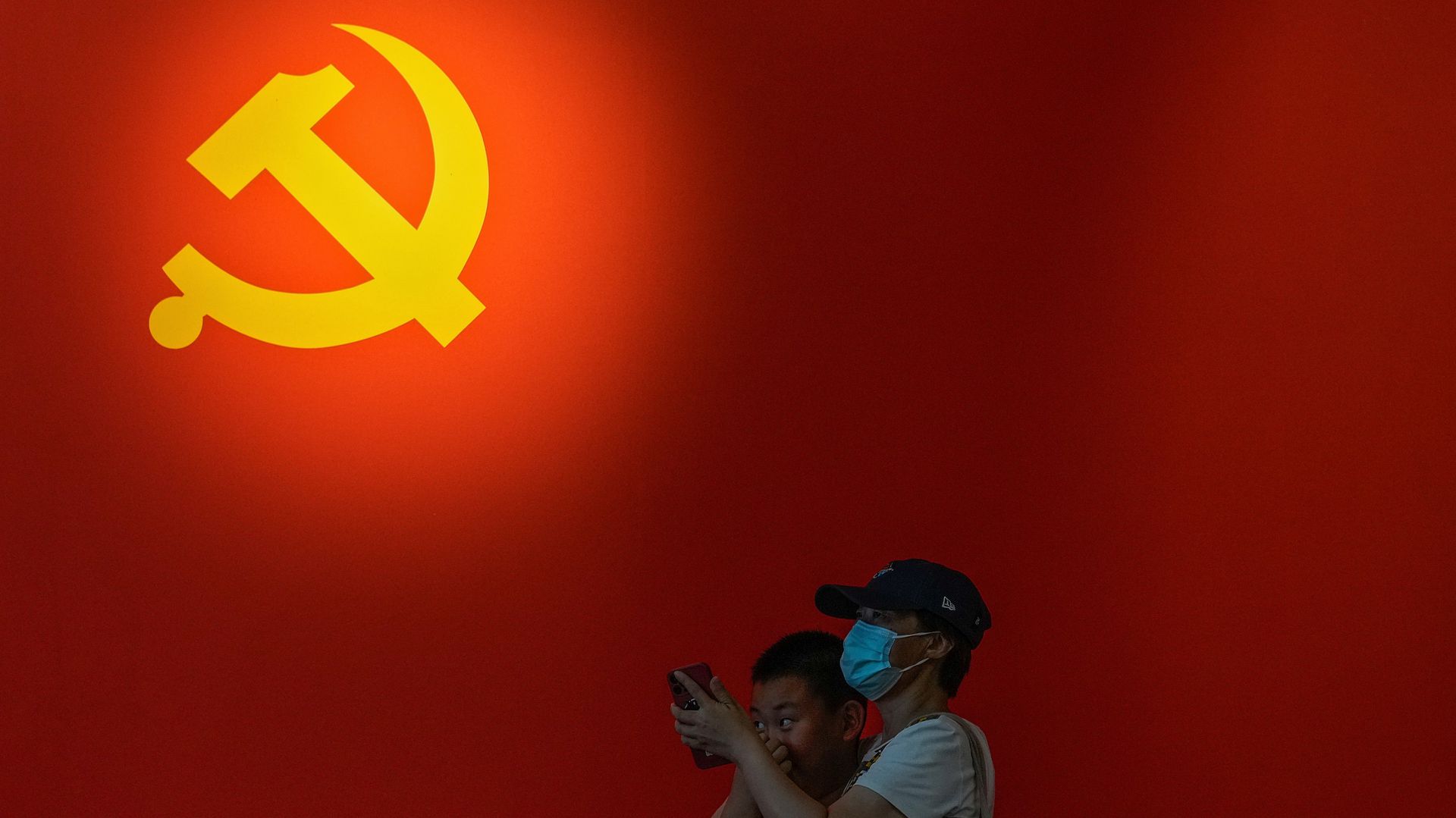6月20日，一名女子与儿童在北京一个展览场地附近路过。当地正举行“红星照耀大运河——中国共产党北京市通州区历史主题展览” 。（AP）