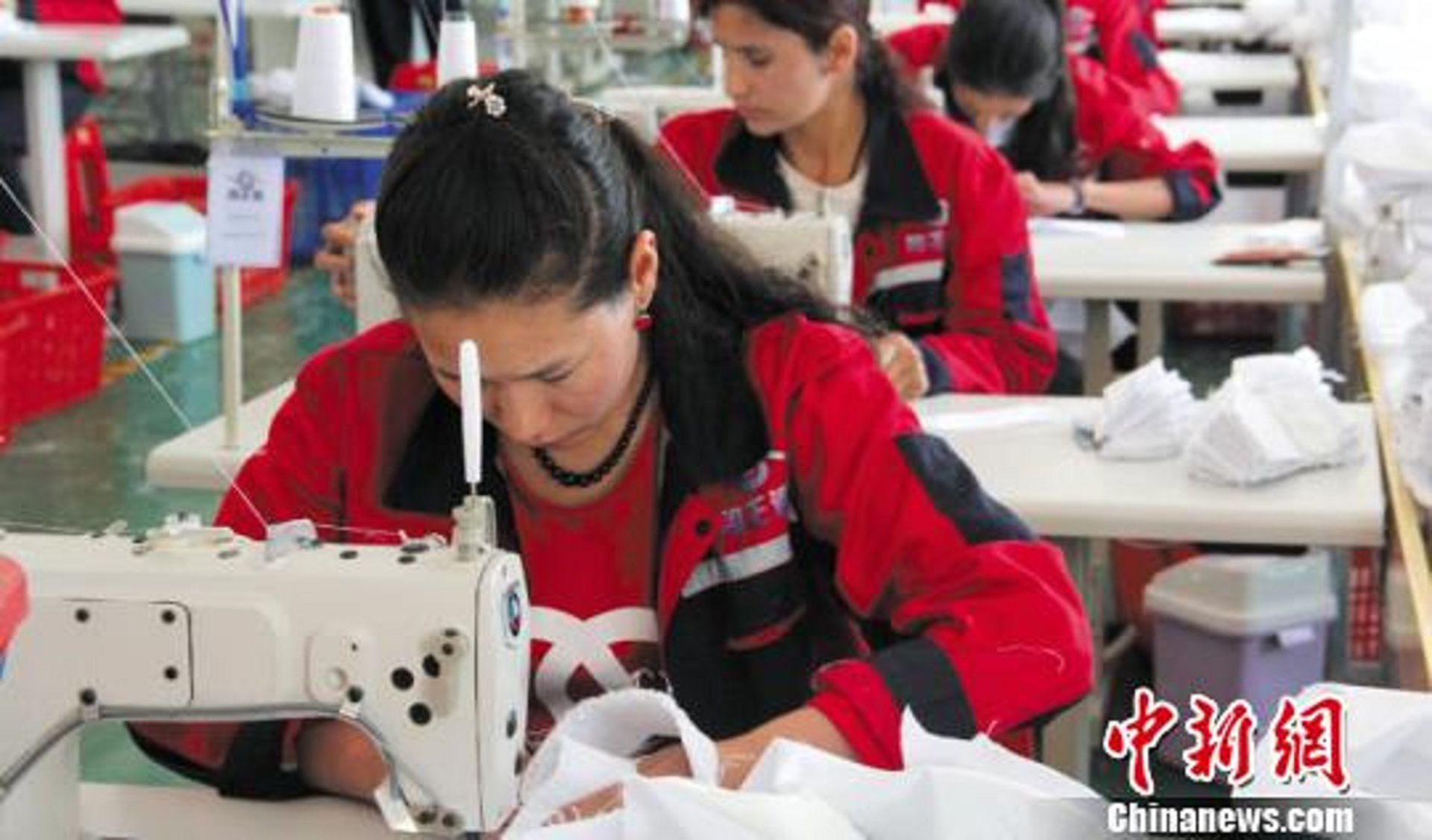 新疆喀什地区塔什库尔干塔吉克自治县纺织工业园区服装厂内，经过技术培训的工人们缝制外裤。（中国新闻网）