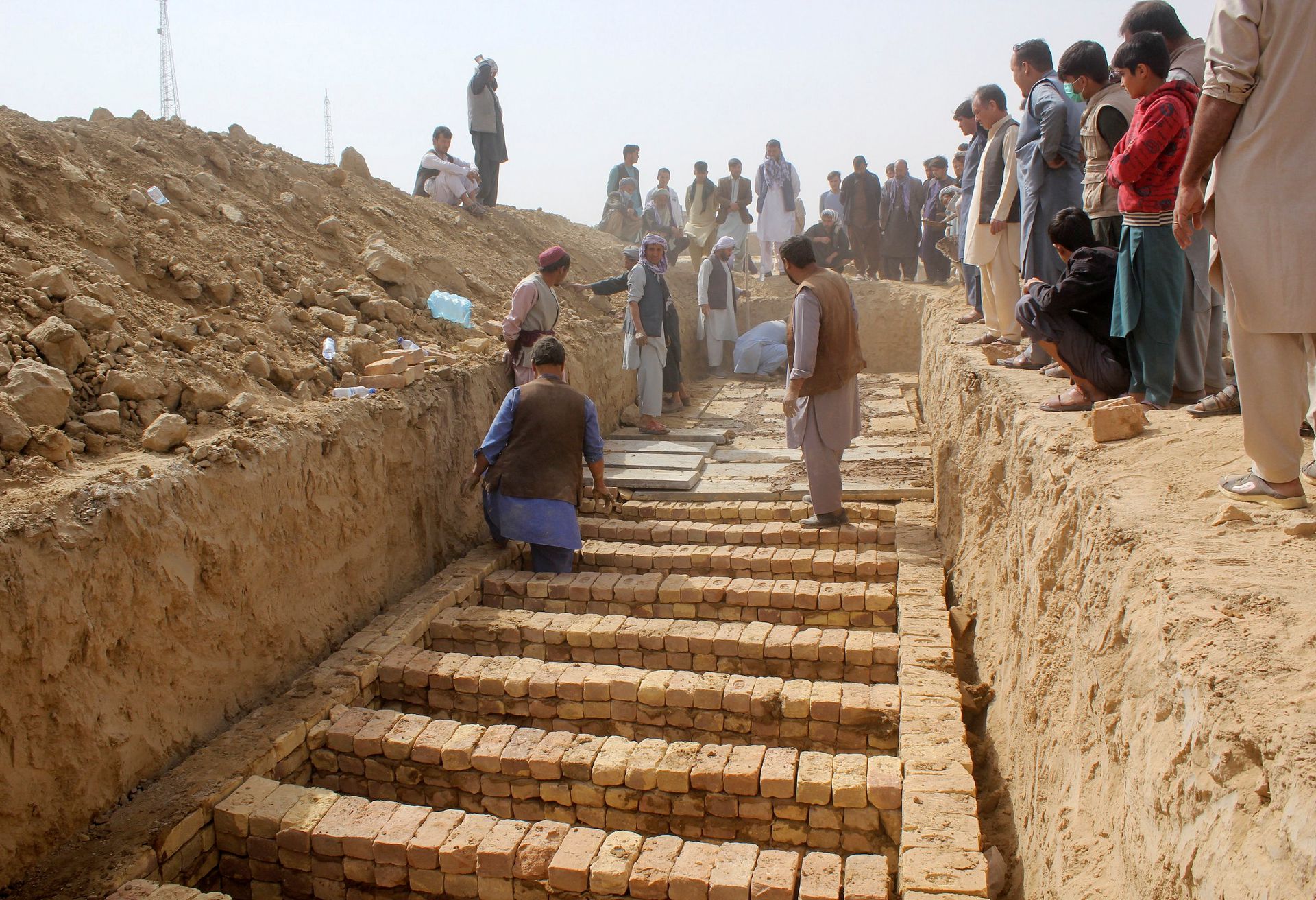 10月9日，几名阿富汗男性在前一天的自杀式爆炸案后挖掘大型坟墓，用来安葬死者。（Reuters）