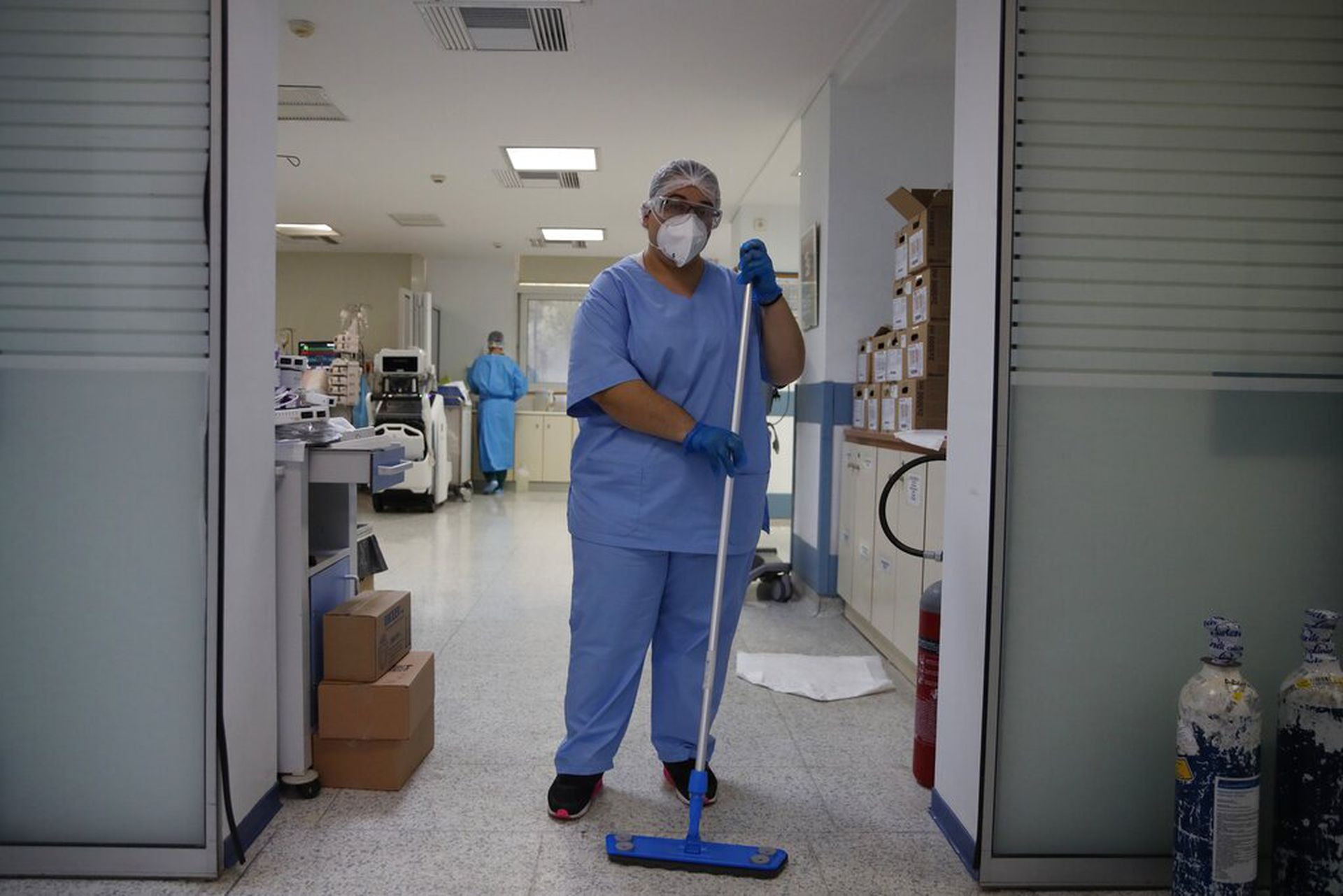 希腊新冠肺炎疫情：图为1月18日雅典一所医院内，一名清洁工人站在深切医疗部门前。（AP）