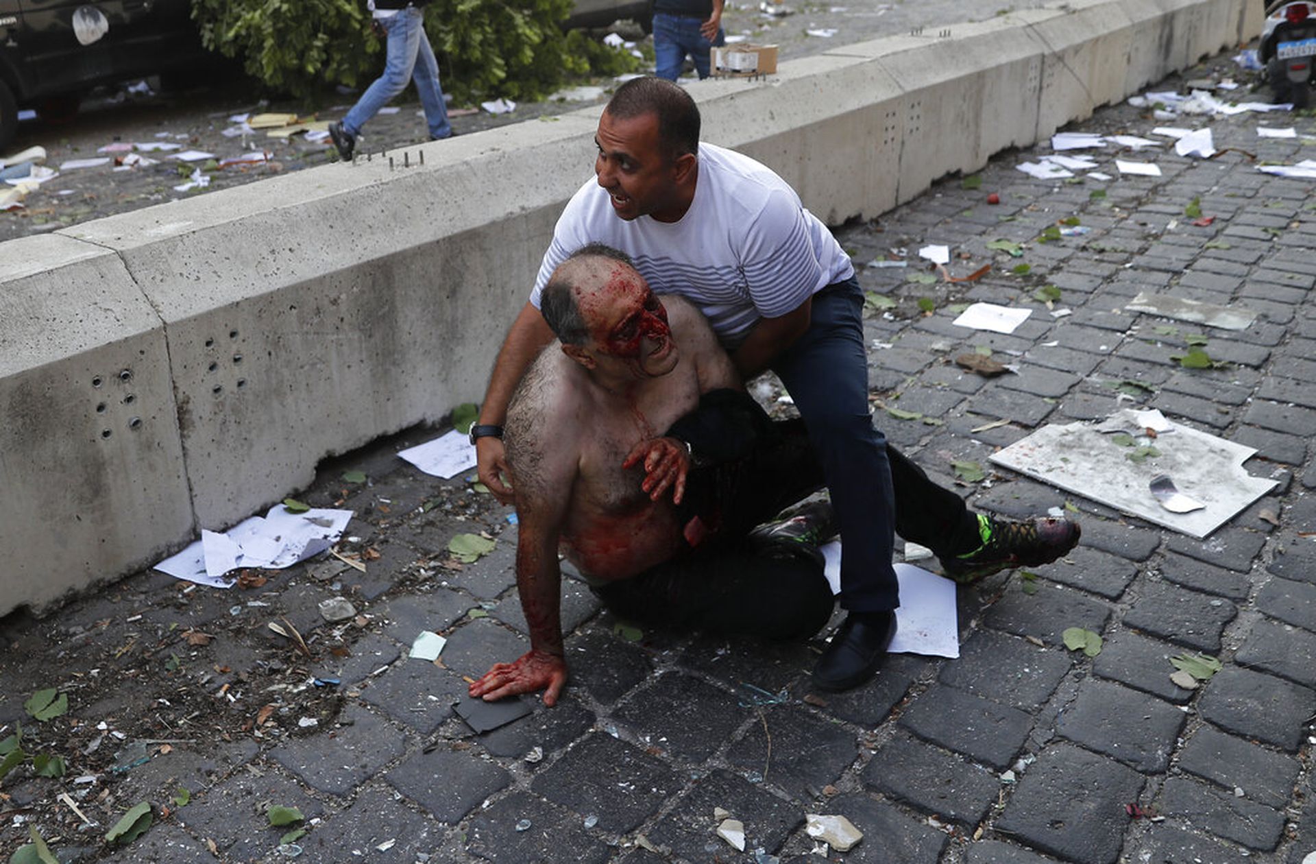 一名男子在爆炸发生后协助另一名伤者。（AP）