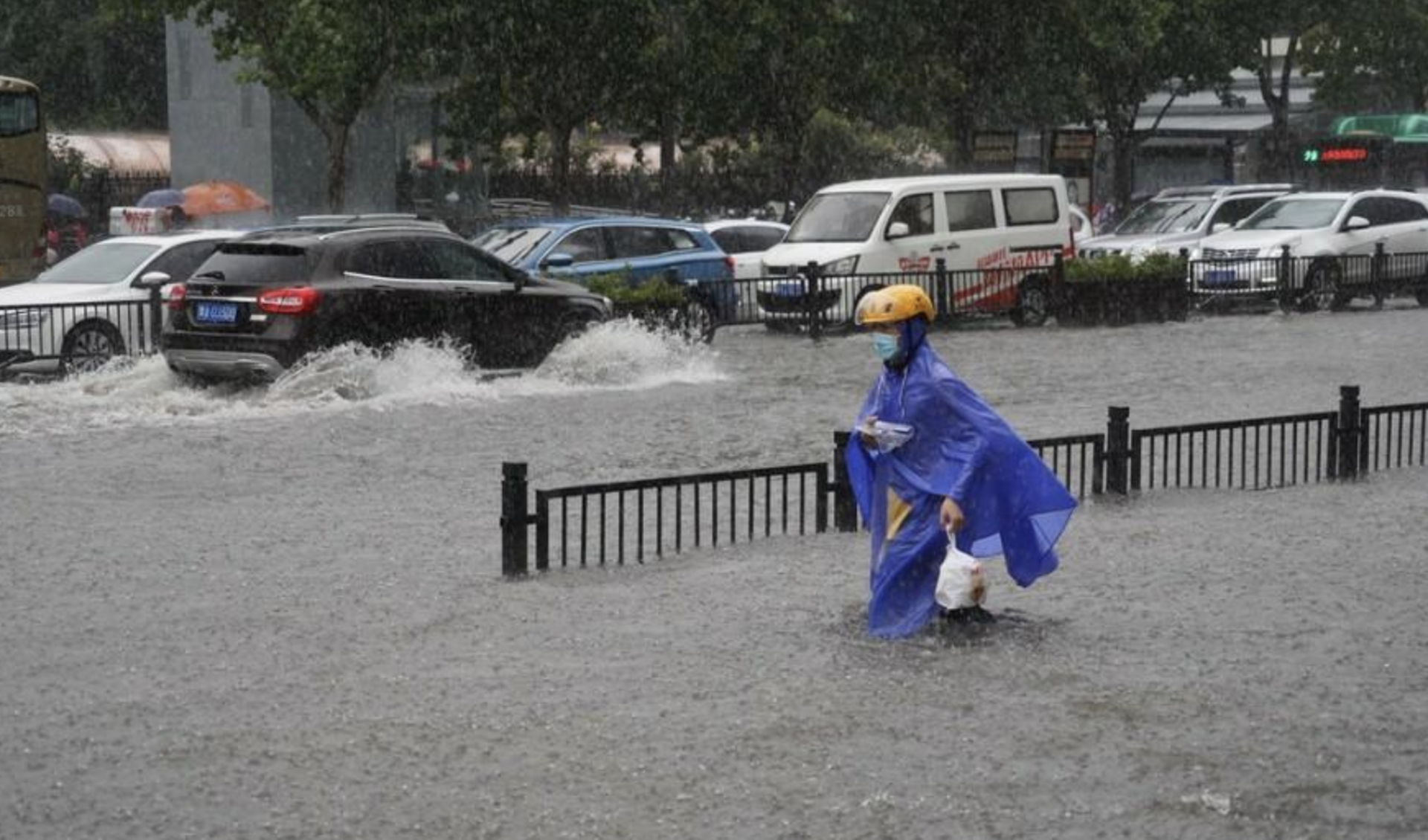 7月20日，郑州连遭暴雨袭击，持续强降雨导致部分街道积水严重，一位外卖小哥淌水前行。（中国网网站截图）