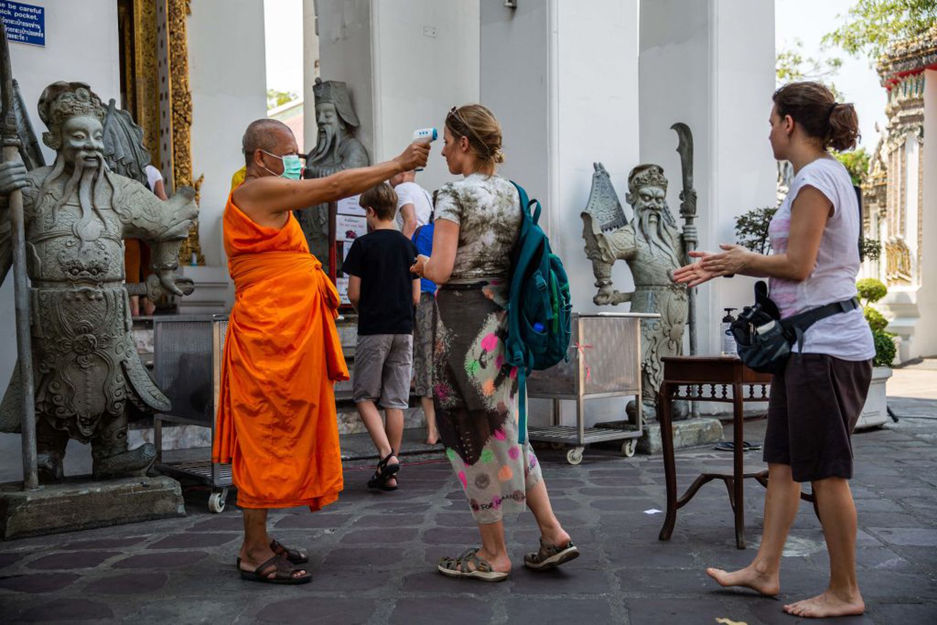 2020年3月13日，外籍游客进入曼谷一间寺庙前接受体温检测。（Getty）