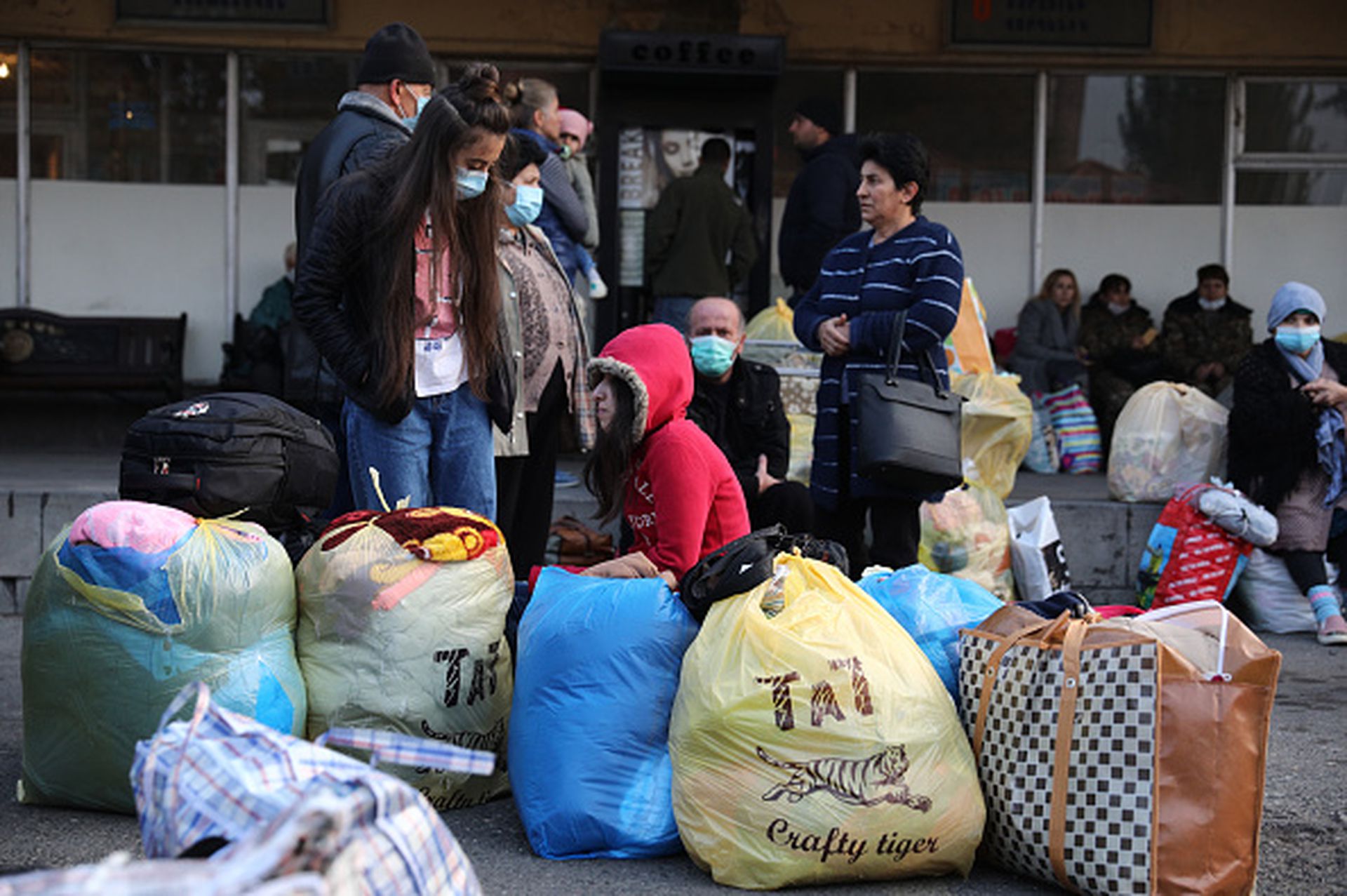 亚美尼亚的国内恶斗，让埃里温方面无暇顾及棘手的纳卡难民问题。随着阿塞拜疆势力的逐步进驻，原本居住在纳卡的亚美尼亚人大部分沦为难民。图为2020年11月17日：纳卡难民拖家带口，聚集在基利基娅汽车站等待开往纳卡自治州首府斯捷潘纳克的班车，该自治州是目前纳卡地区唯一属于亚美尼亚的领土。（Getty Images）