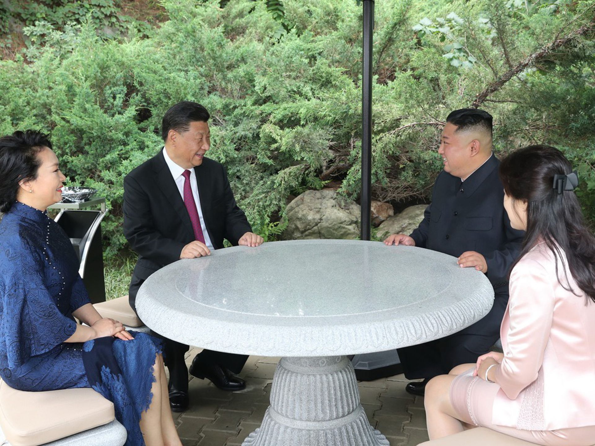 习近平访问朝鲜期间，金正恩夫妇陪同习近平夫妇在凉亭聊天。（新华社）
