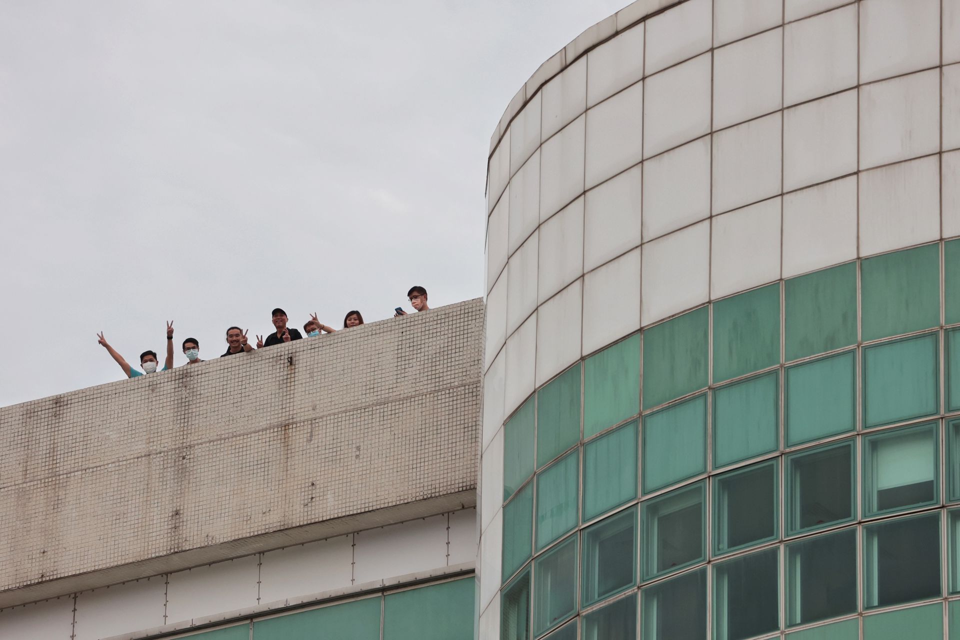 6月22日下午有《苹果日报》员工在将军澳工业村壹．苹果大楼顶层，凭栏向在外采访的记者举行胜利手势。（李泽彤摄）