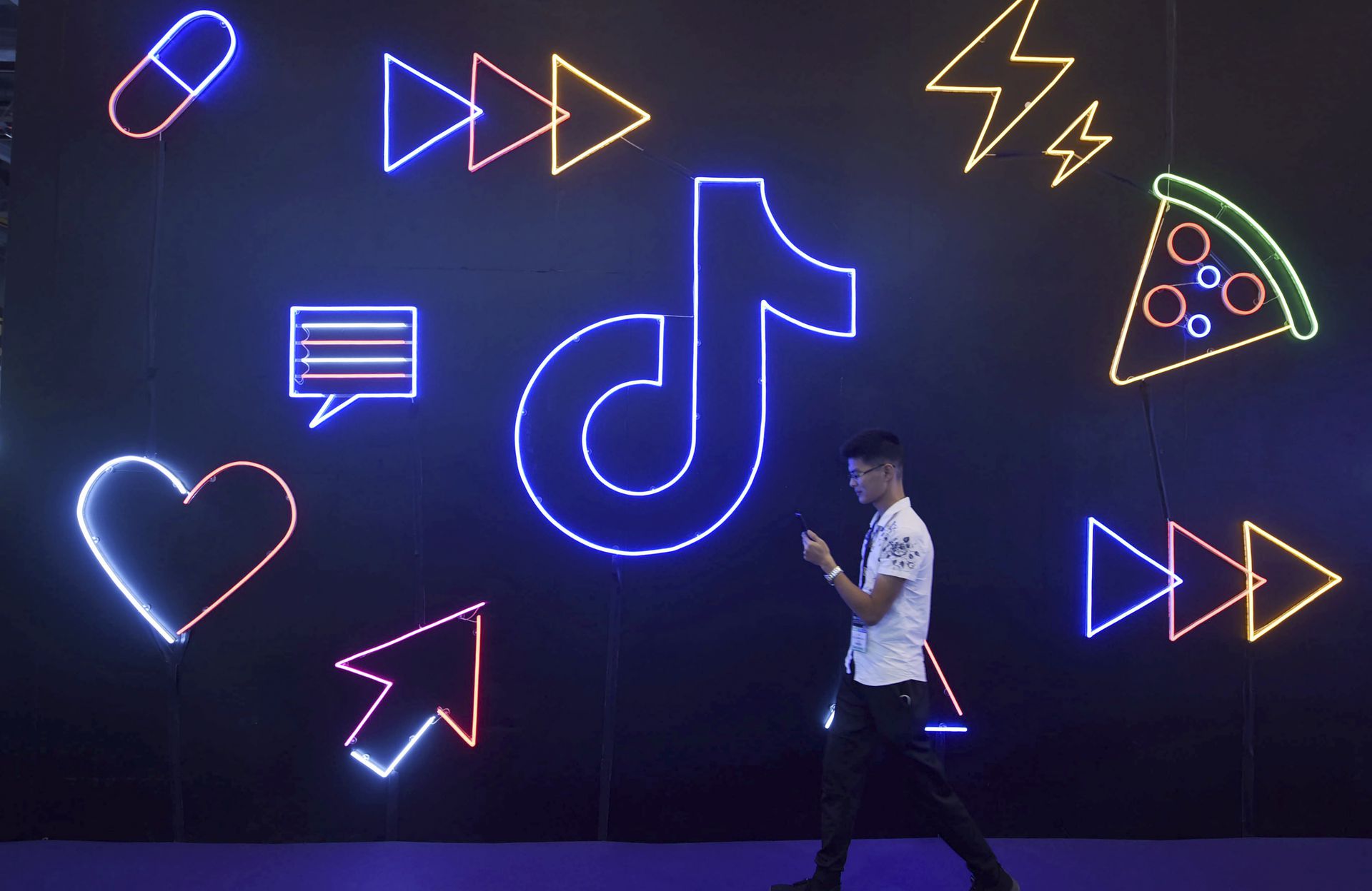 TikTok是抖音国际版，在多国拥有众多粉丝。图为2019年10月18日，一名男子参加在中国杭州市举行的博览会，场内有一个抖音的灯光装置。（AP）