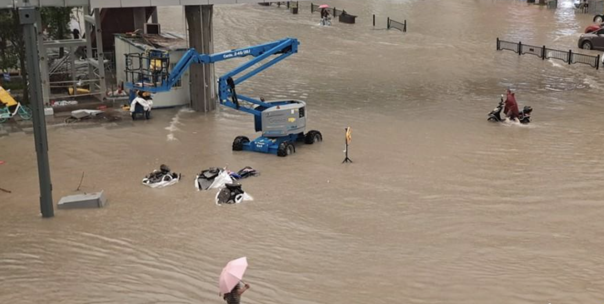 7月20日，河南郑州暴雨如注。图为航拍紫荆山路商城路内涝成河，汽车、共享单车被泡在水里。（中国网网站截图）