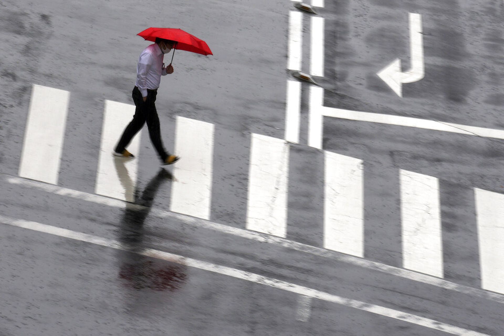 日本新冠肺炎疫情：图为6月17日日本东京一名男子在骤雨中过马路。（AP）