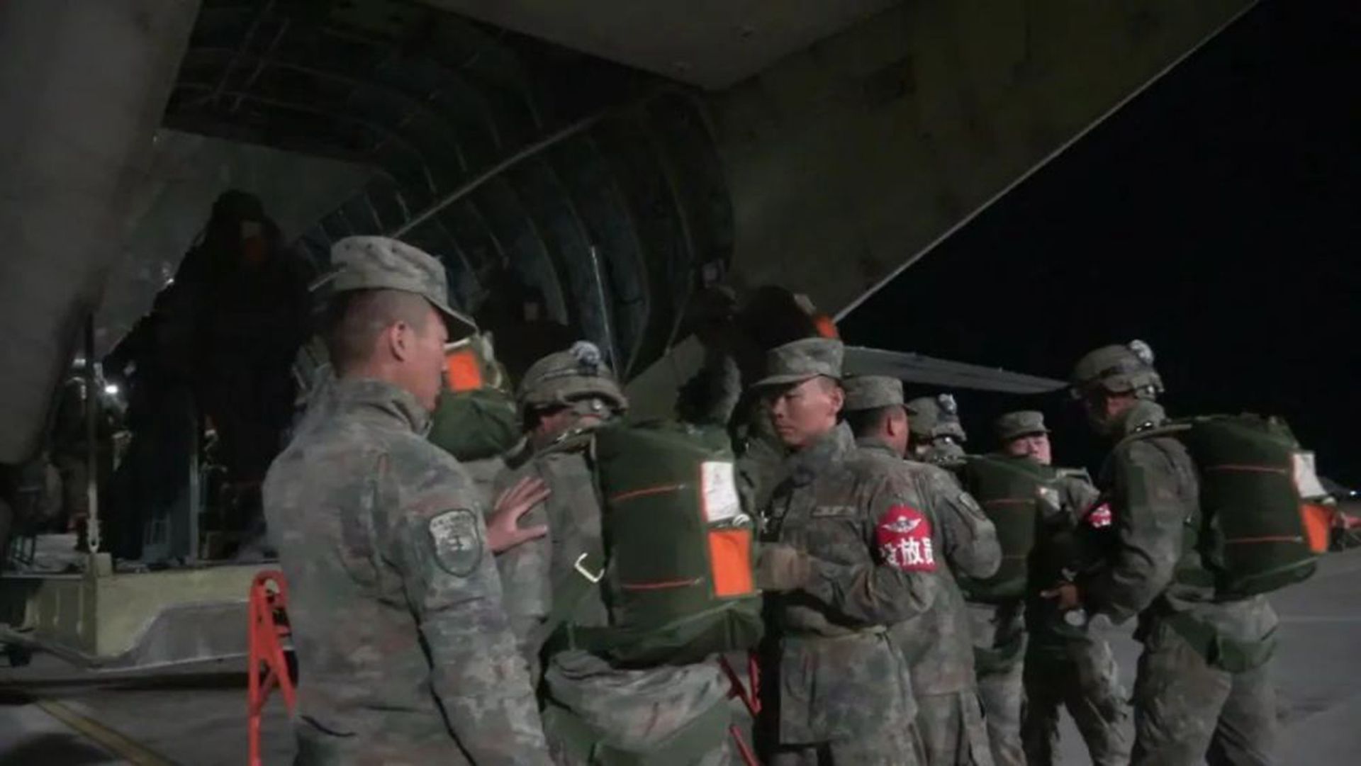 携带伞降器材的特战队员准备登机。（中国央视截图）