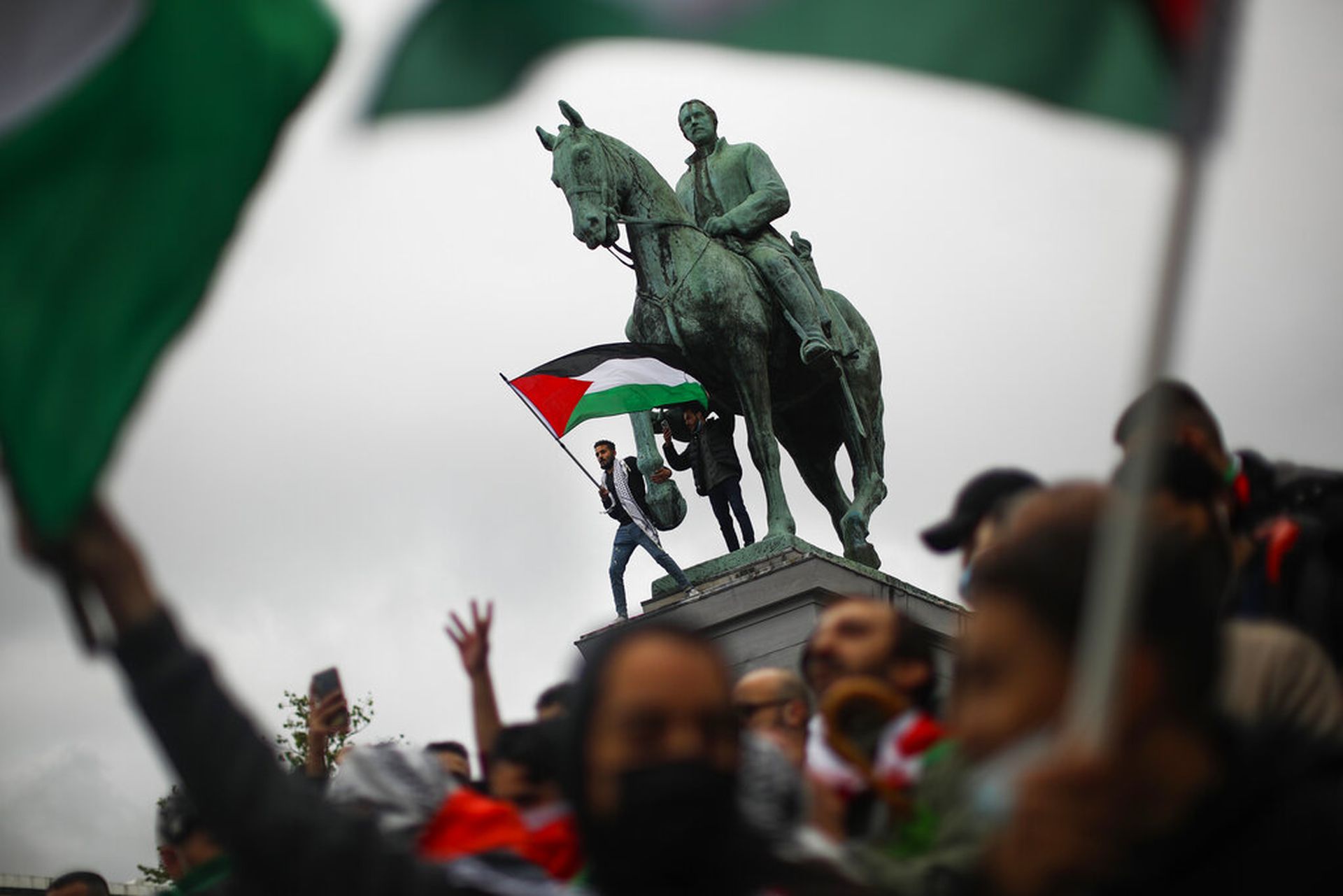 5月15日，一名男子在比利时首都布鲁塞尔出席支持巴人集会期间挥动巴勒斯坦国旗。（AP）